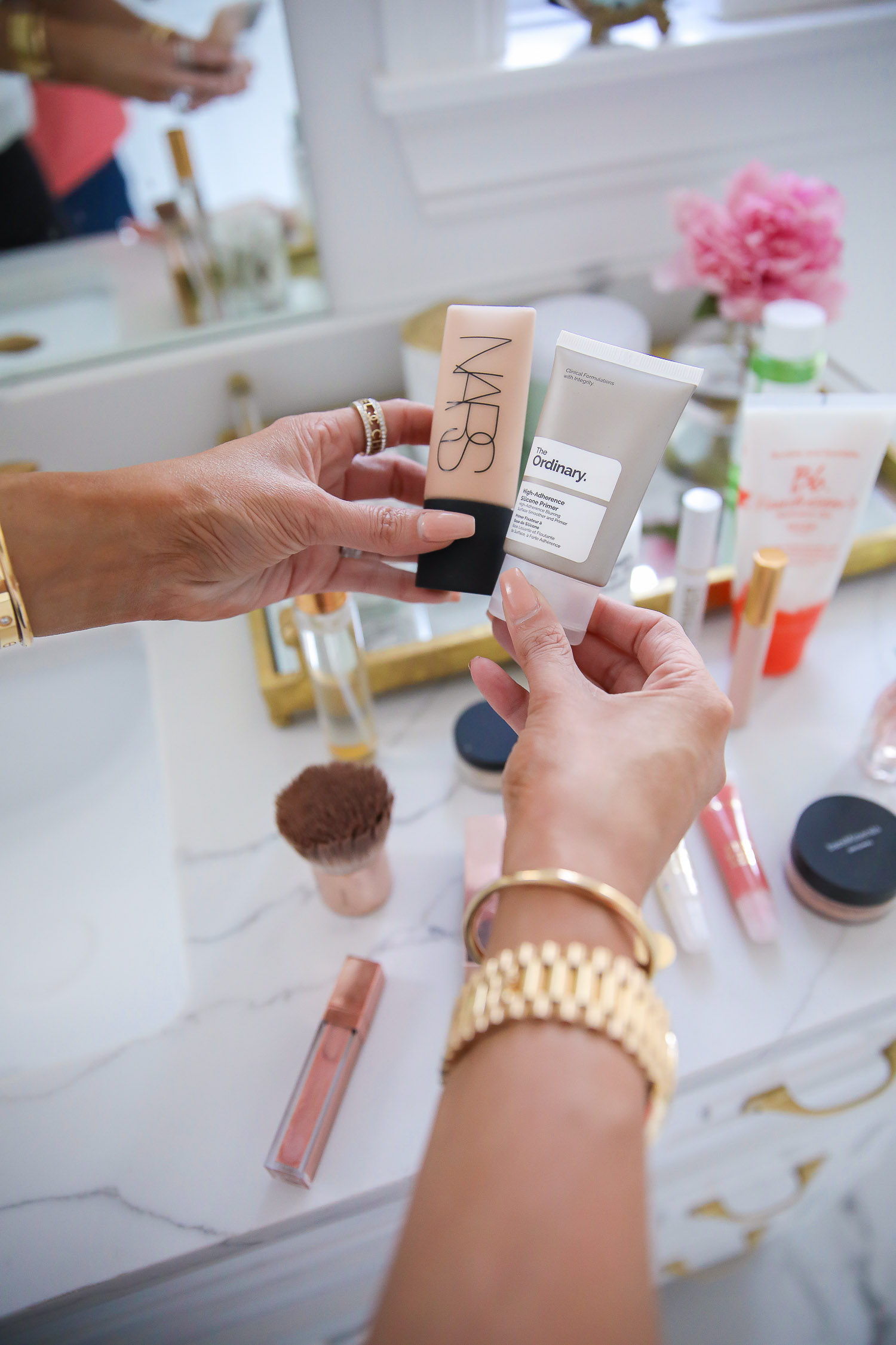 Sephora Favorites by popular US beauty blog, The Sweetest Thing: image of Emily Gemma wearing a white lace camisole and black jeans and holding a tube of Nars foundation and The Ordinary primer. 