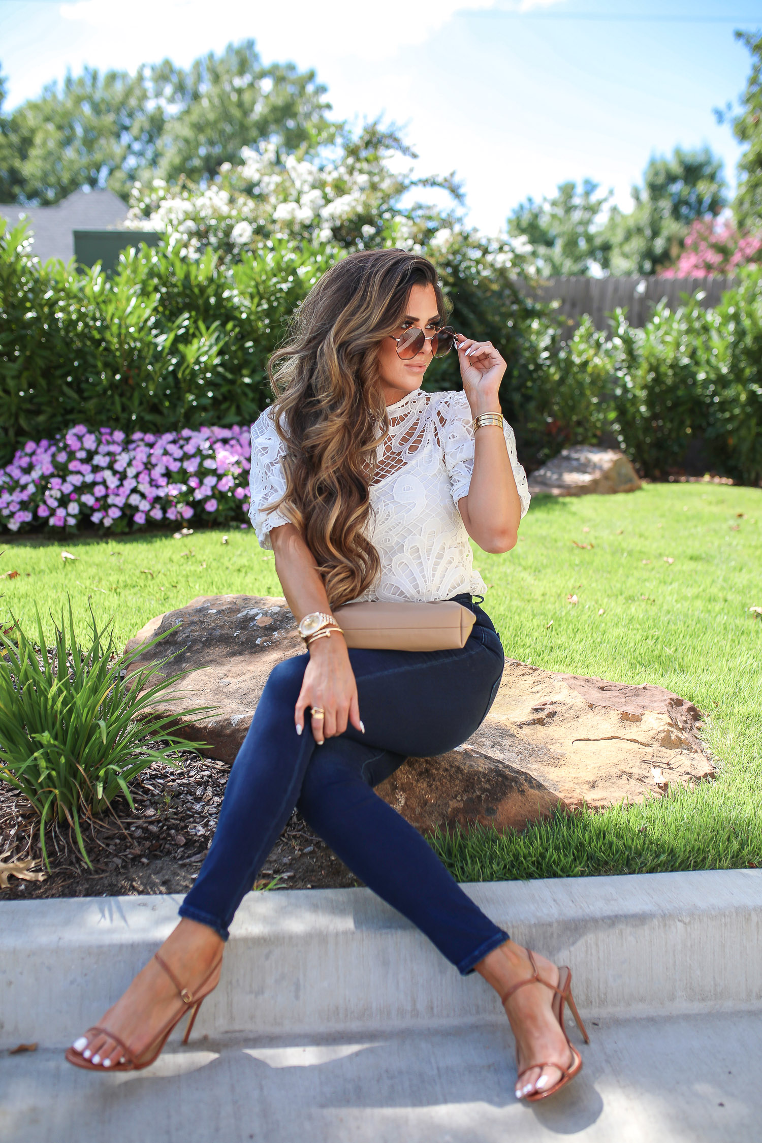express fall 2020, express fall fashion trends 2020 pinterest, emily ann gemma, zimmermann dupe lookalike top, chloe dupe sunglasses | Fall Clothing by popular US fashion blog, The Sweetest Thing: image of Emily Gemma sitting down outside and wearing a Express Lace Puff Sleeve Top, Express High Waisted Luxe Comfort Knit Faded Skinny Jeans, Express Octagon Cut-Out Sunglasses, Express Thin Strap Textured Heels, Chanel earrings, and Cartier bracelets. 