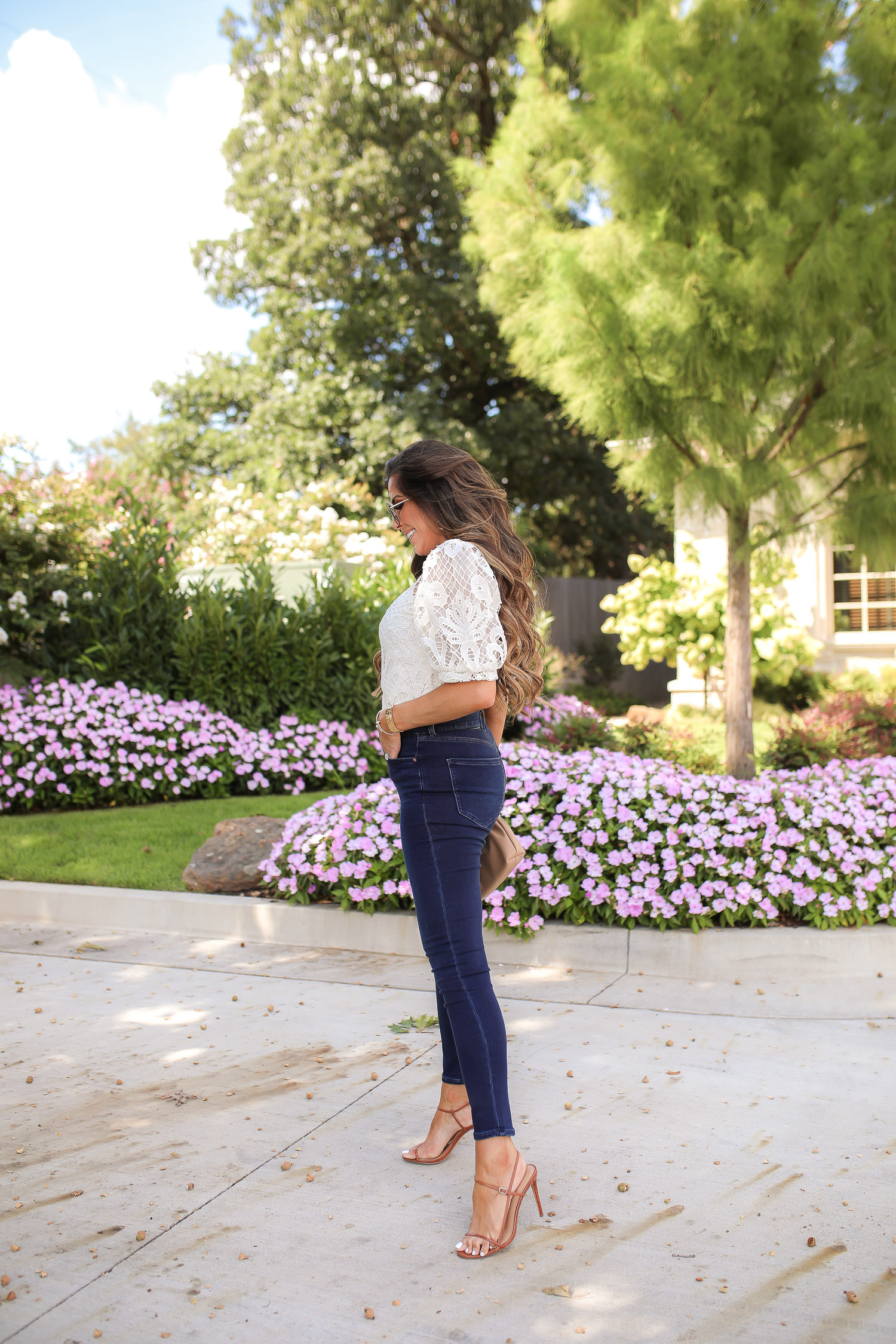 express fall 2020, express fall fashion trends 2020 pinterest, emily ann gemma, zimmermann dupe lookalike top, chloe dupe sunglasses | Fall Clothing by popular US fashion blog, The Sweetest Thing: image of Emily Gemma sitting down outside and wearing a Express Lace Puff Sleeve Top, Express High Waisted Luxe Comfort Knit Faded Skinny Jeans, Express Octagon Cut-Out Sunglasses, Express Thin Strap Textured Heels, Chanel earrings, and Cartier bracelets. 