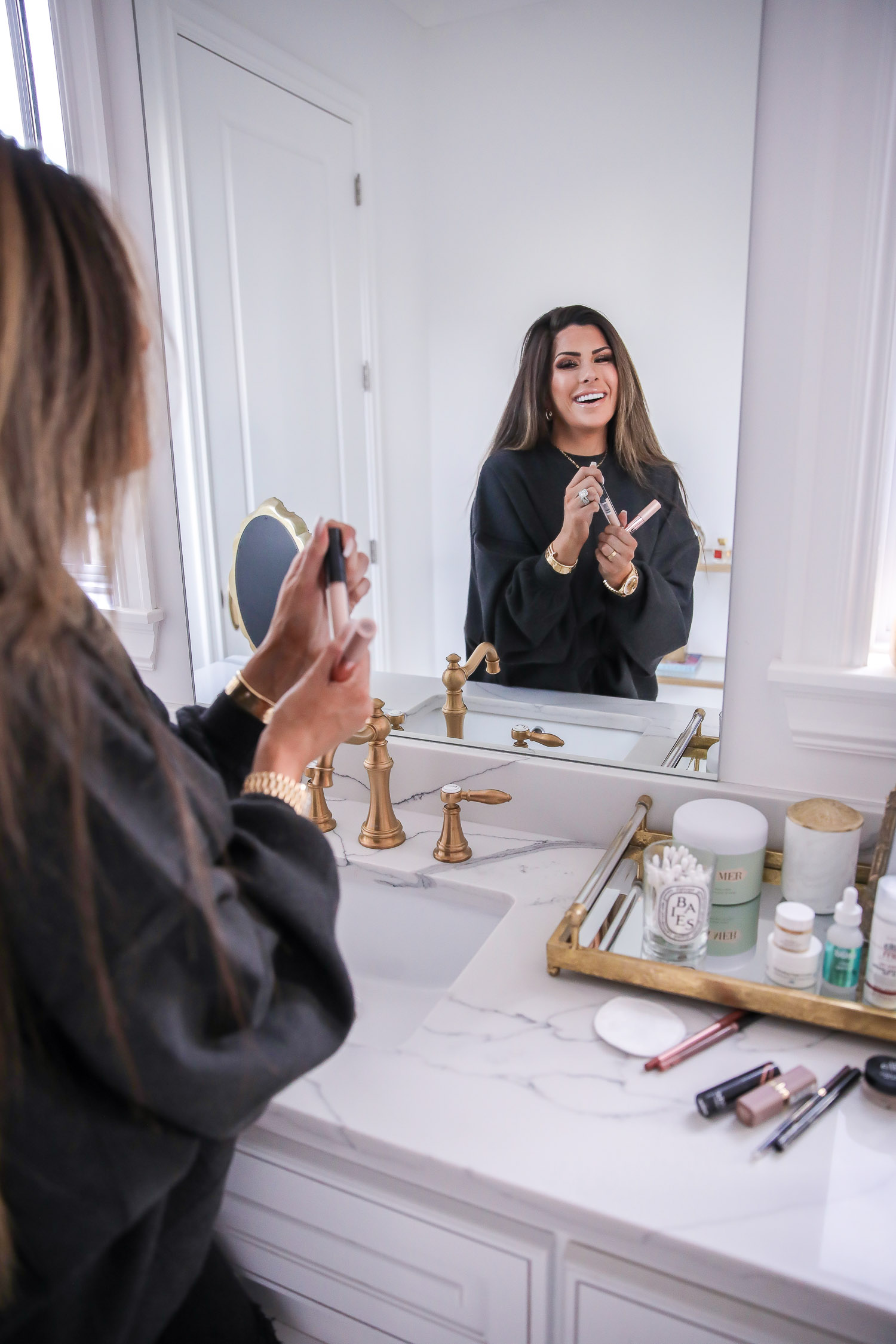 Drugstore Makeup by popular US beauty blog, The Sweetest Thing: image of Emily Gemma holding drugstore lip products in her hands. 