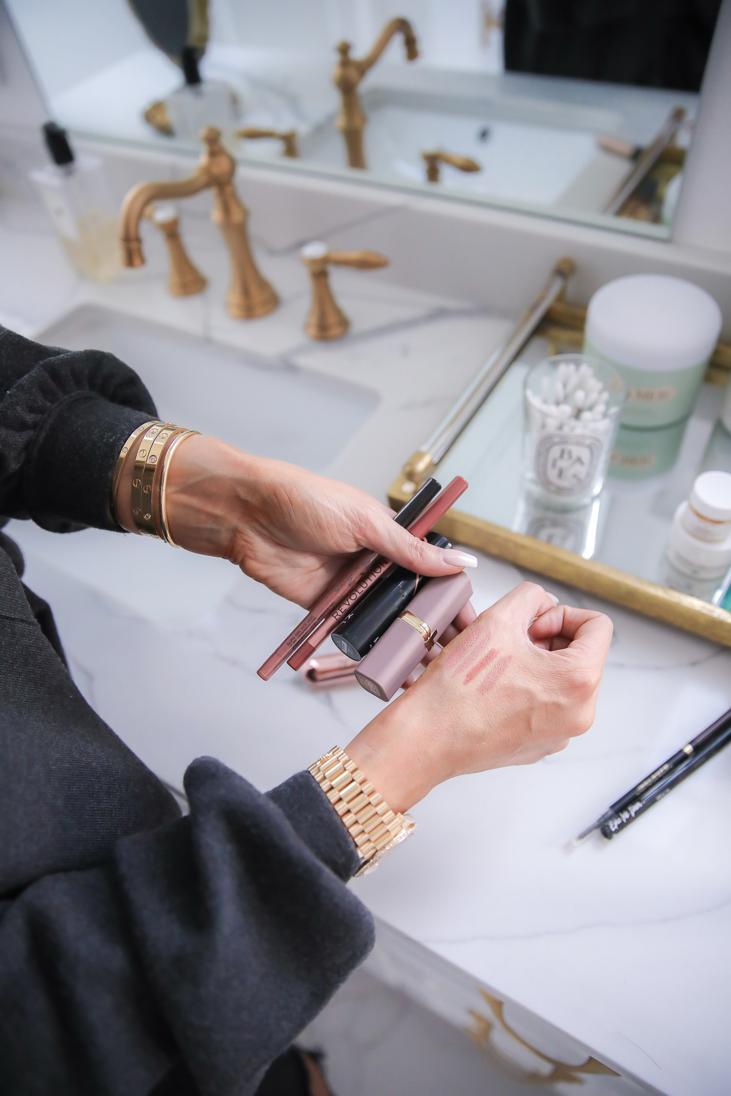 Drugstore Makeup by popular US beauty blog, The Sweetest Thing: image of Emily Gemma holding lip products in her hand. 