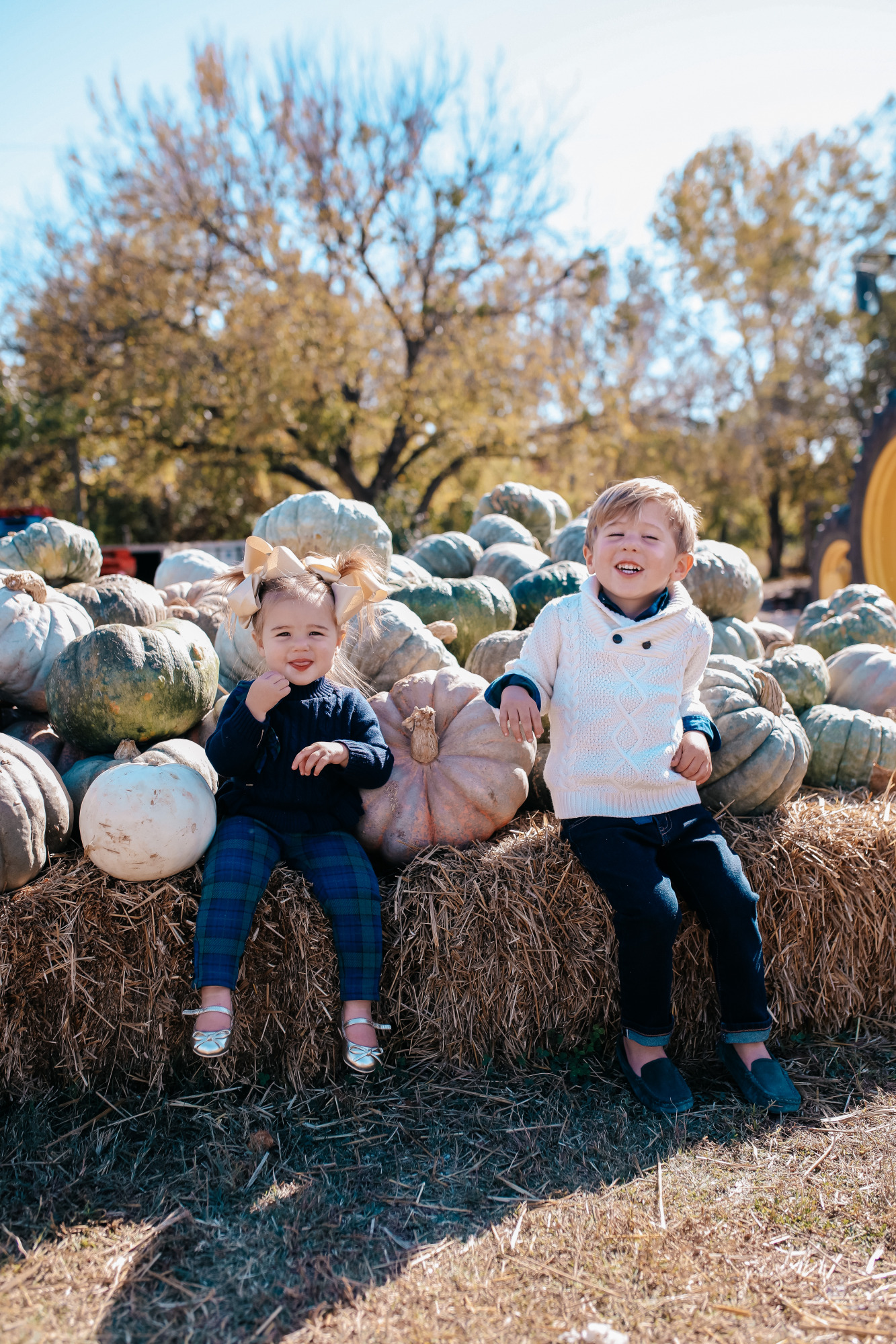 janie and jack kids clothing fall 2020, kids fall fashion 2020, the sweetest thing blog17 | Janie and Jack Kids Clothing by popular US fashion blog, The Sweetest Thing: image of two kids sitting next to a pile of pumpkins and wearing a Janie and Jack PLAID POPLIN SHIRT, Janie and Jack SHAWL COLLAR PULLOVER, Janie and Jack SLIM SELVEDGE JEAN IN MOONLIGHT INDIGO WASH, Janie and Jack LEATHER TRIM BELT, Janie and Jack ARGYLE SOCK, Janie and Jack SUEDE DRIVING SHOE, Janie and Jack PEPLUM BOW SWEATER, Janie and Jack PLAID PONTE BUTTON CUFF PANT, and Janie and Jack METALLIC BOW FLAT.
