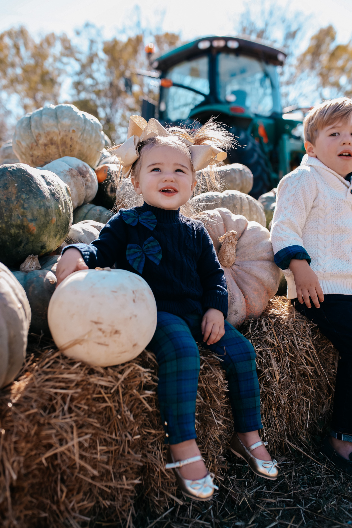 janie and jack kids clothing fall 2020, kids fall fashion 2020, the sweetest thing blog17 |janie and jack kids clothing fall 2020, kids fall fashion 2020, the sweetest thing blog17 | Janie and Jack Kids Clothing by popular US fashion blog, The Sweetest Thing: image of two kids sitting next to a pile of pumpkins and wearing a Janie and Jack PLAID POPLIN SHIRT, Janie and Jack SHAWL COLLAR PULLOVER, Janie and Jack SLIM SELVEDGE JEAN IN MOONLIGHT INDIGO WASH, Janie and Jack LEATHER TRIM BELT, Janie and Jack ARGYLE SOCK, Janie and Jack SUEDE DRIVING SHOE, Janie and Jack PEPLUM BOW SWEATER, Janie and Jack PLAID PONTE BUTTON CUFF PANT, and Janie and Jack METALLIC BOW FLAT.
