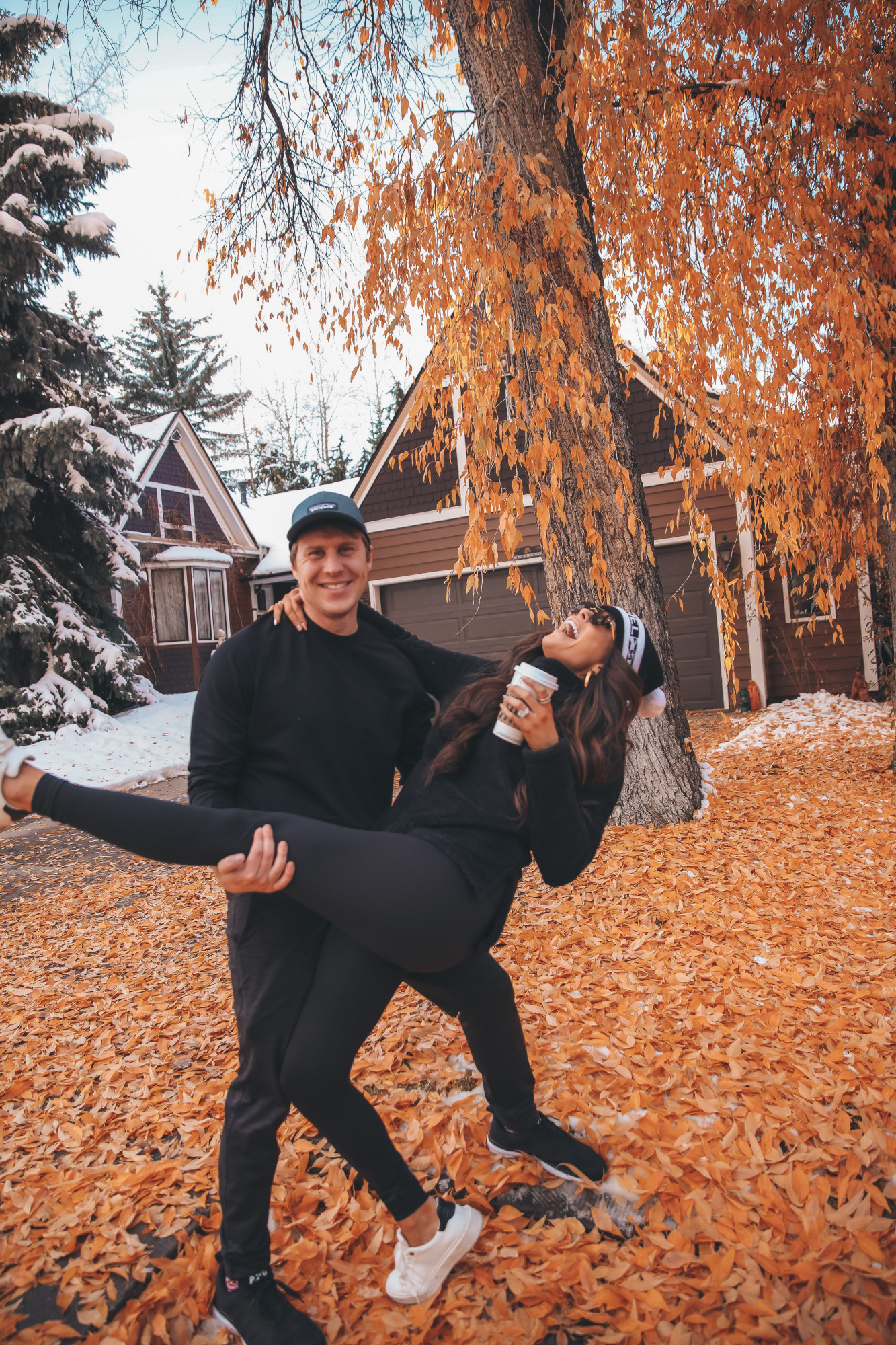 Aspen fall 2020, zella workout clothing review, Emily Gemma, Chanel Beanie, |Athleisure Wear by popular US fashion blog, The Sweetest Thing: image of a husband wearing a Logo Baseball Cap PATAGONIA, Pyrite Slim Fit Joggers ZELLA, and Crewneck Fleece Sweatshirt ZELLA, and a wife wearing a Furry Fleece Funnel Neck Pullover ZELLA, Booty Boost Active 7/8 Leggings SPANX,Charlie Platform Sneaker STEVE MADDEN,Panarea 60mm Aviator Sunglasses LE SPECS, and Lip Cheat Lip Liner CHARLOTTE TILBURY and standing together outside on a leaf covered driveway. 
