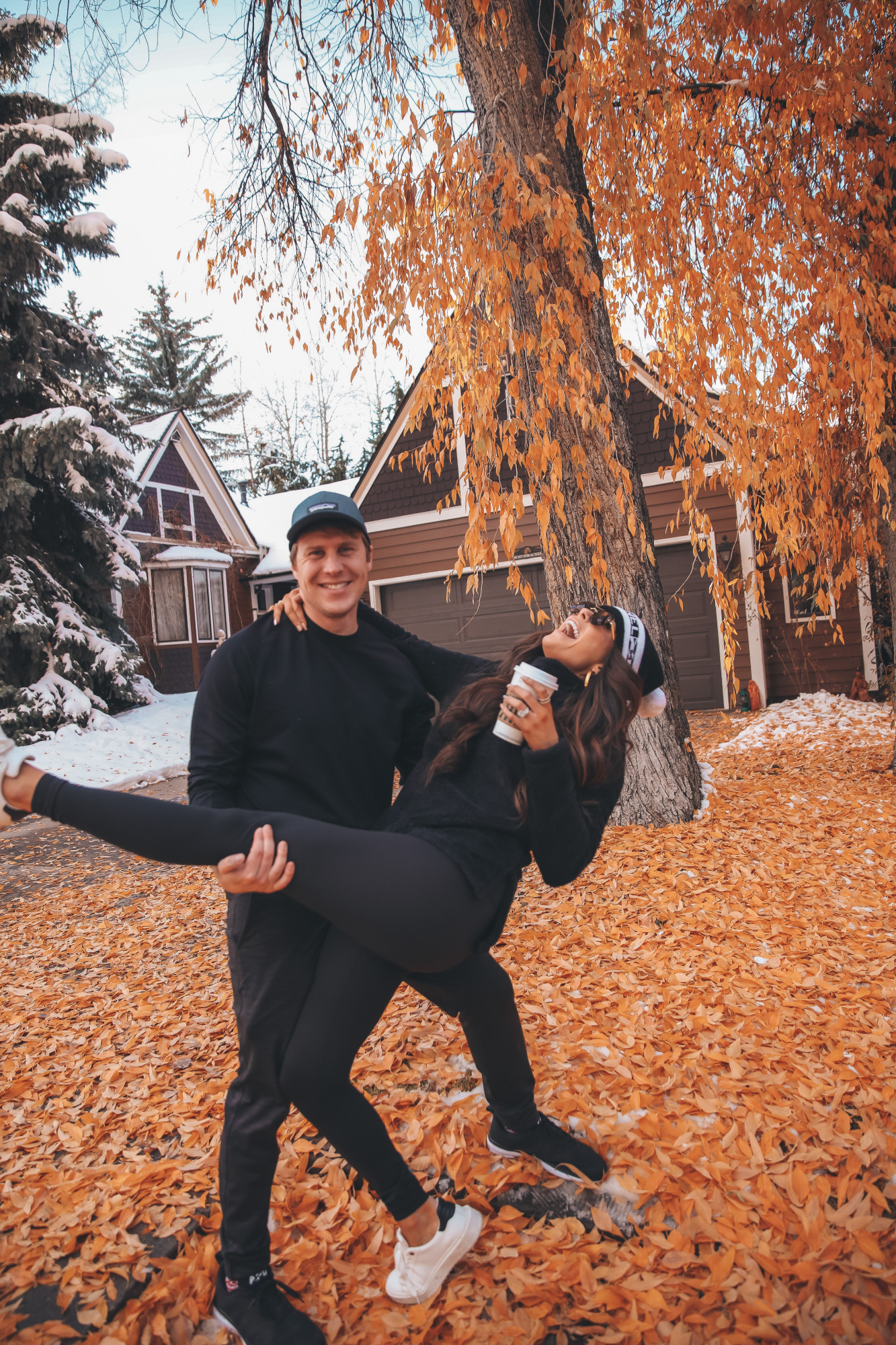 Aspen fall 2020, zella workout clothing review, Emily Gemma, Chanel Beanie, |Athleisure Wear by popular US fashion blog, The Sweetest Thing: image of a husband wearing a Logo Baseball Cap PATAGONIA, Pyrite Slim Fit Joggers ZELLA, and Crewneck Fleece Sweatshirt ZELLA, and a wife wearing a Furry Fleece Funnel Neck Pullover ZELLA, Booty Boost Active 7/8 Leggings SPANX,Charlie Platform Sneaker STEVE MADDEN,Panarea 60mm Aviator Sunglasses LE SPECS, and Lip Cheat Lip Liner CHARLOTTE TILBURY and standing together outside on a leaf covered driveway.