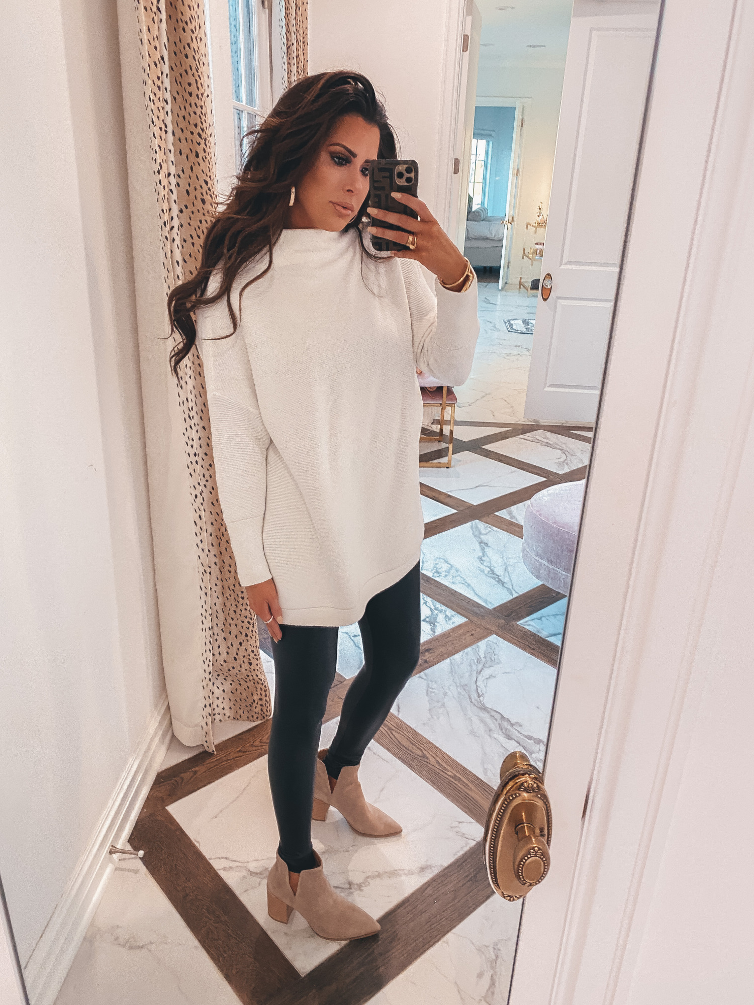 Thanksgiving Outfits by popular US fashion blog, The Sweetest Thing: image of Emily Gemma wearing a oversized cream colord mock neck sweater, Commando black leather leggings, Steve Madden Boots, Cartier rings and bracelets, Bracha necklace and The Styled Collection earrings. 