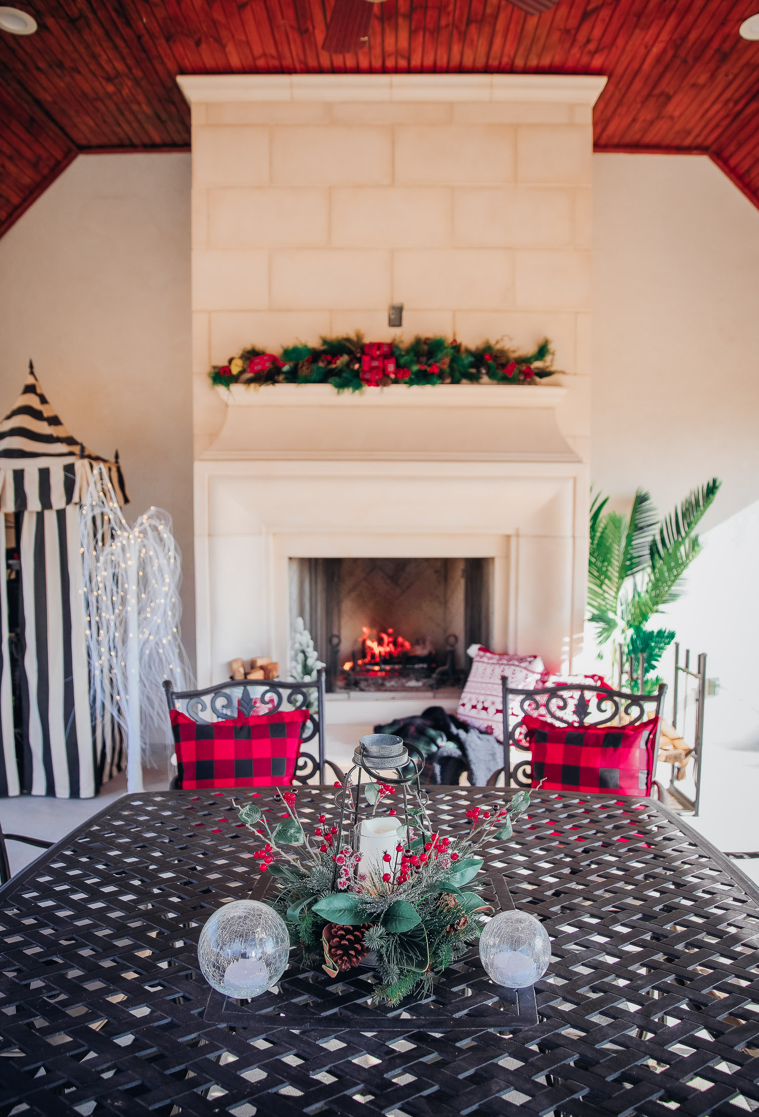 backyard decor christmas, outdoor pool christmas decor, walmart pool ornament, emily gemma backyard | Christmas Pool Decorations by popular US life and style blog, The Sweetest Thing: image of a pool house decorated with Christmas garland, black and red buffalo check throw pillows, Christmas tree decor, and candles. 