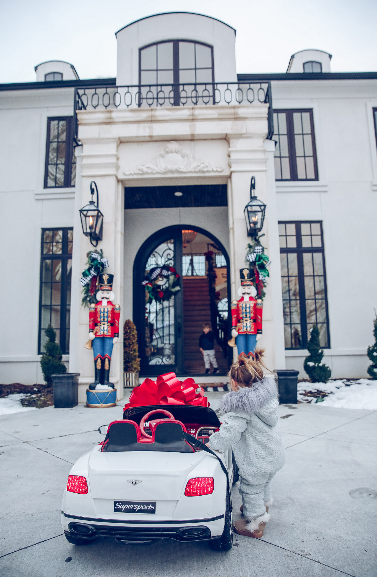 Christmas outdoor decorations home depot, emily gemma home, christmas wreaths on gates with bow, blow up nutcrackers, |Holiday Home Decor by popular US life and style blog, The Sweetest Thing: image of the front of a house decorated with nutcrackers and Christmas wreaths. 