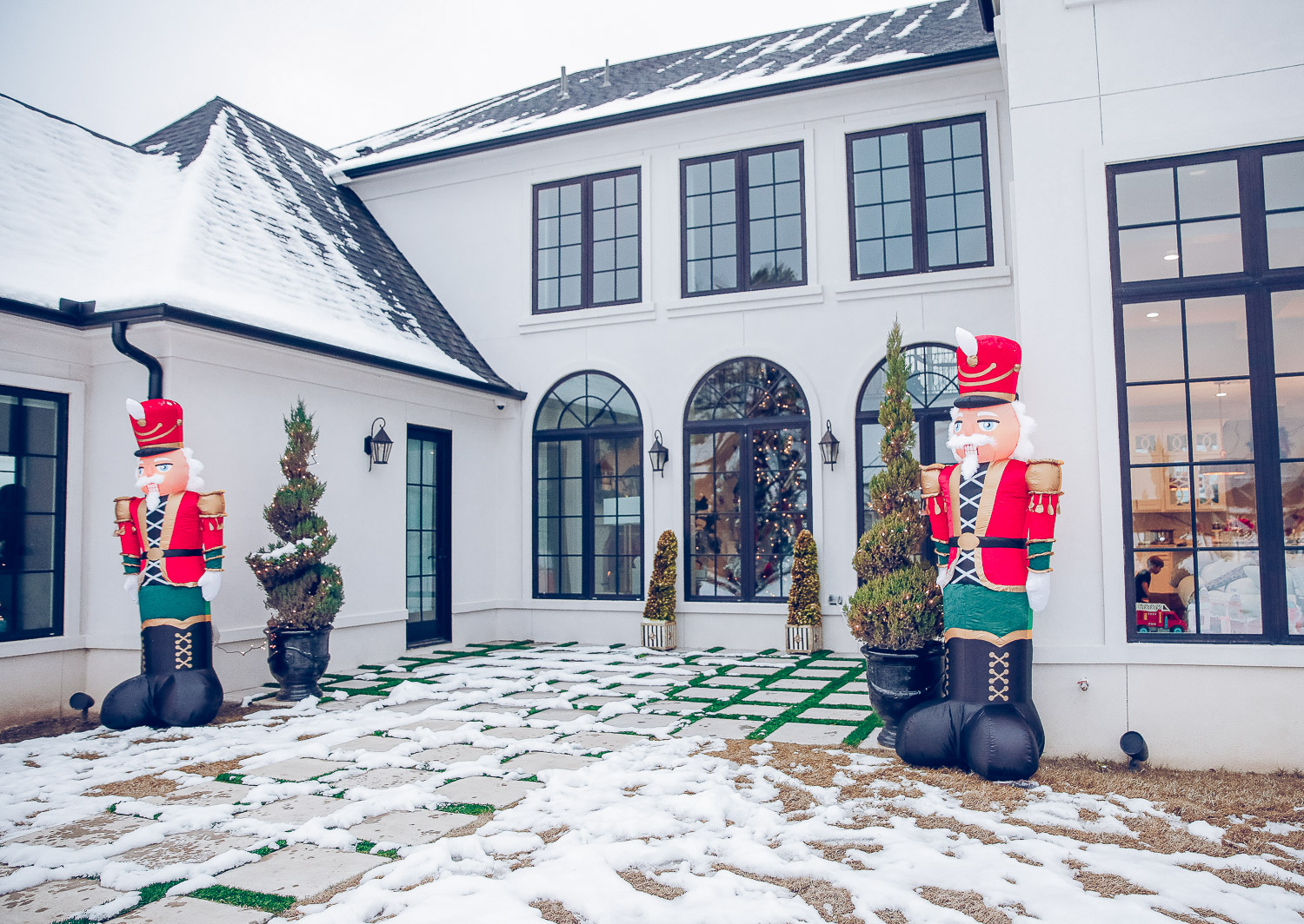 Christmas outdoor decorations home depot, emily gemma home, christmas wreaths on gates with bow, blow up nutcrackers, |Holiday Home Decor by popular US life and style blog, The Sweetest Thing: image of a backyard decorated with topiary trees, white lights, and inflatable nutcrackers. 