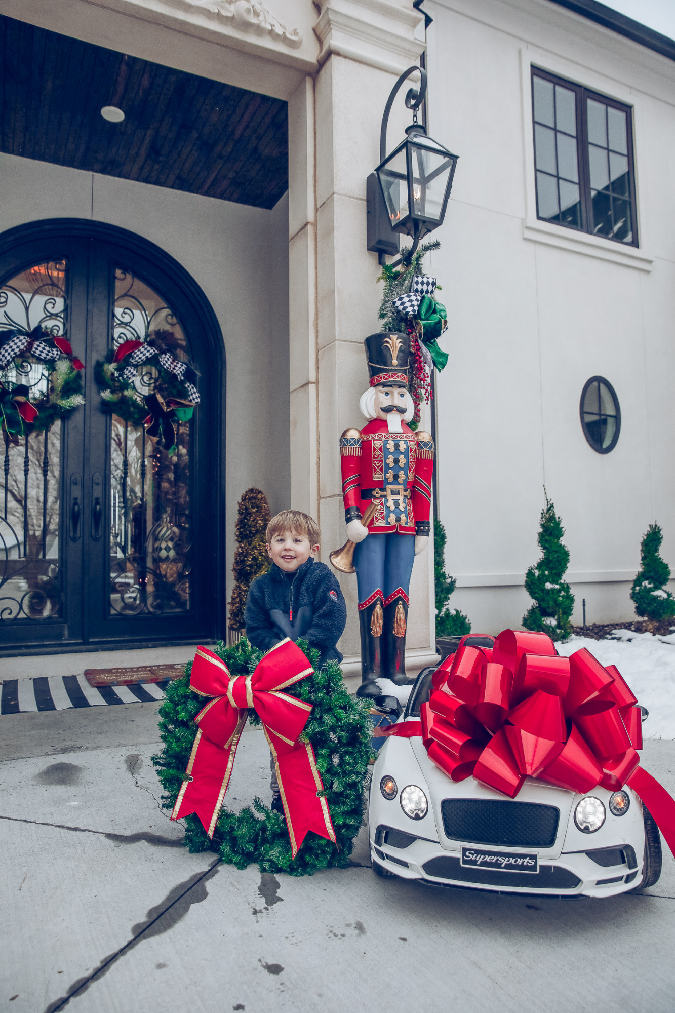 Christmas outdoor decorations home depot, emily gemma home, christmas wreaths on gates with bow, blow up nutcrackers, |Holiday Home Decor by popular US life and style blog, The Sweetest Thing: image of the front of a house decorated with nutcrackers and Christmas wreaths.