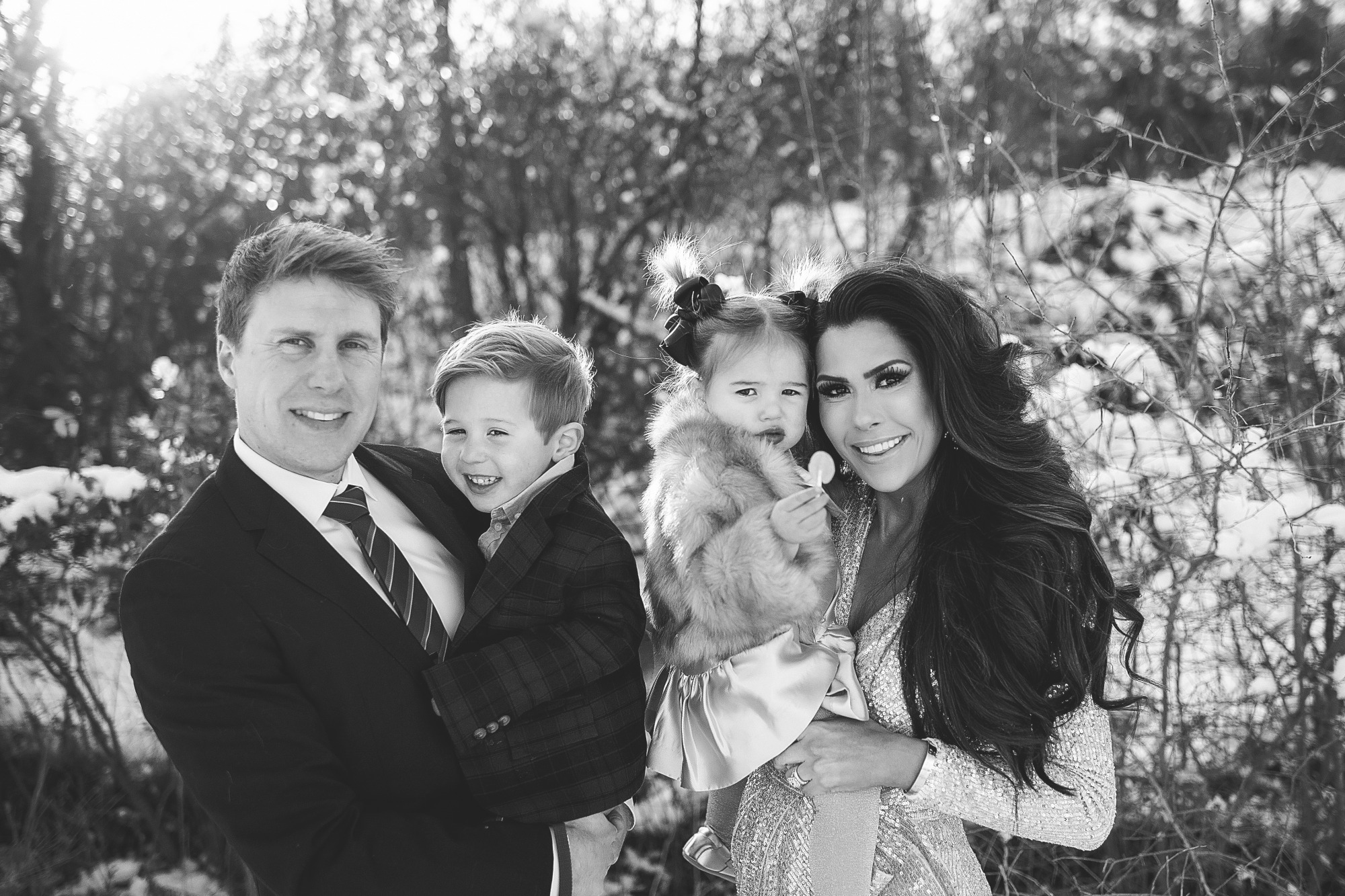 Family Christmas Card by popular US lifestyle blog, The Sweetest Thing: image of a family standing together in the snow with their dog and wearing a Eliza J sequin dress, blue suit, blue and green plaid blazer and tan pants, and a faux fur coat and gold dress. 