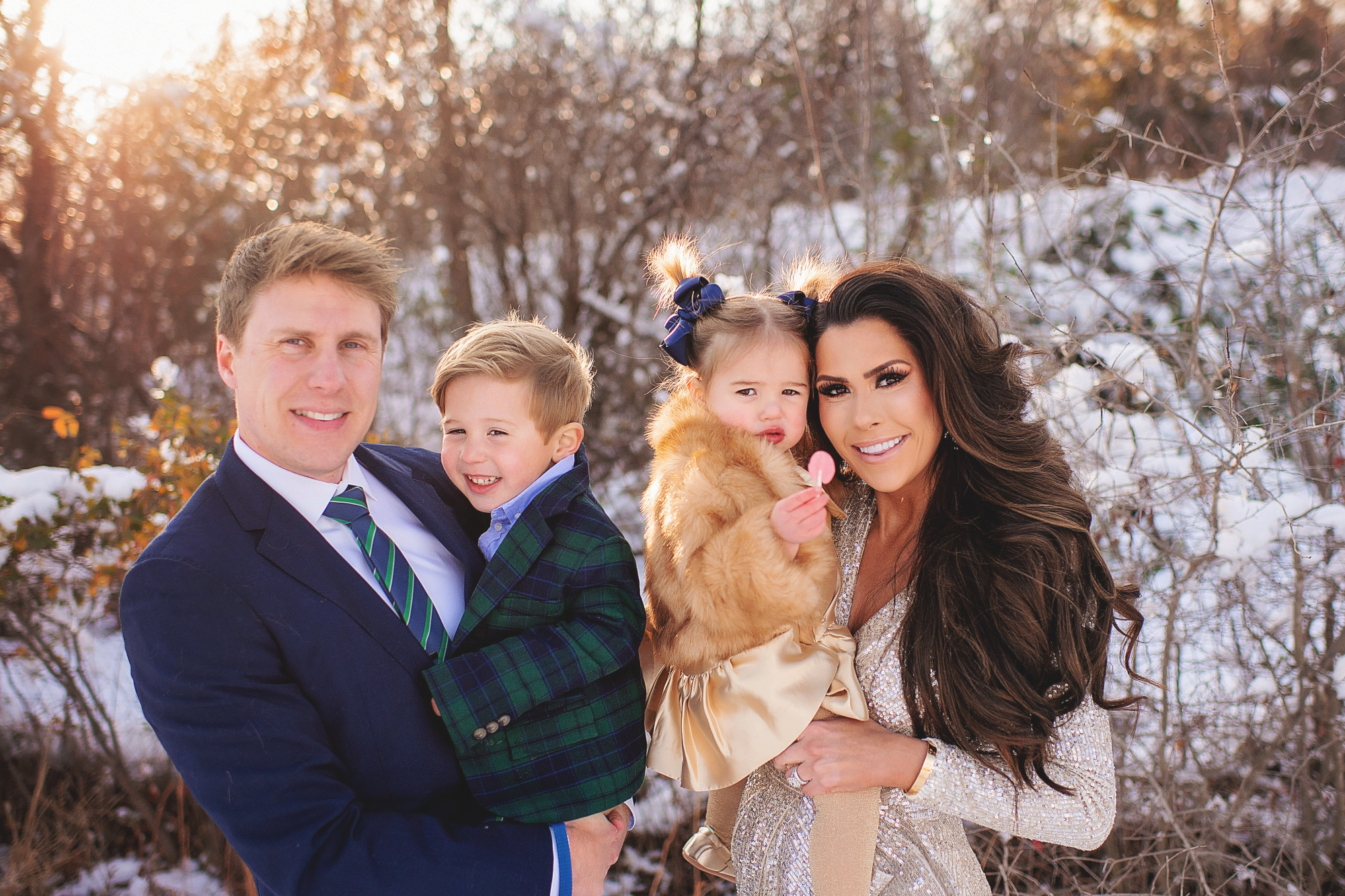 Family Christmas Card by popular US lifestyle blog, The Sweetest Thing: image of a family standing together in the snow with their dog and wearing a Eliza J sequin dress, blue suit, blue and green plaid blazer and tan pants, and a faux fur coat and gold dress. 
