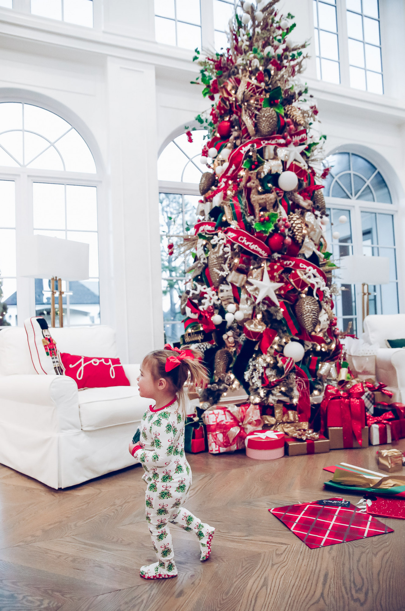 walmart gift wrap christmas 2020, shop hello holidays christmas tree, magnetic me PJs, emily ann gemma-10 |Gift Wrapping Ideas by popular US life and style blog, The Sweetest Thing: image of a little girl wearing Magnetic Me Christmas pjs while standing next to Christmas wrapping paper spread all over the floor in front of a Christmas tree with red, green and gold ornaments.