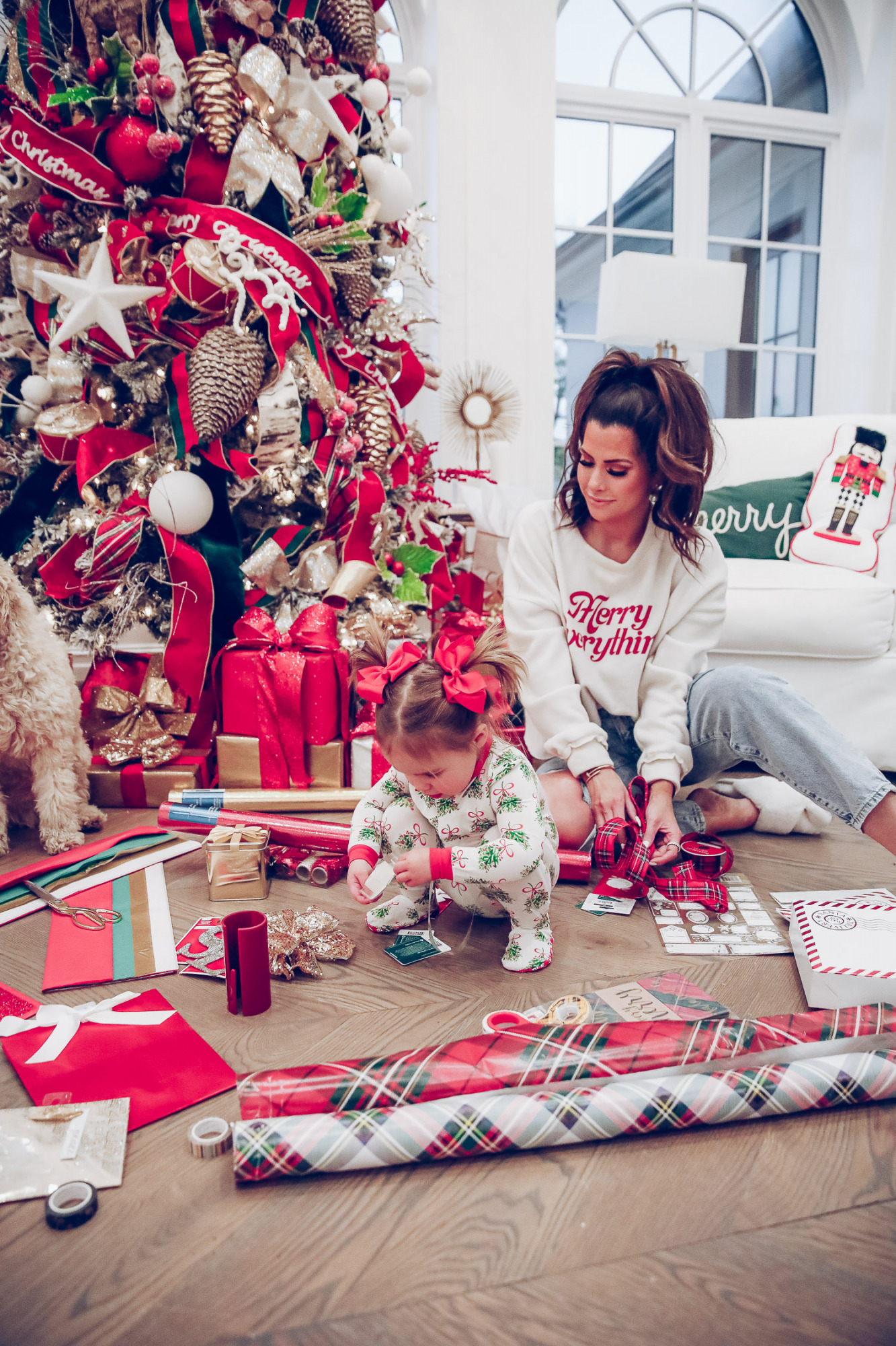 walmart gift wrap christmas 2020, shop hello holidays christmas tree, magnetic me PJs, emily ann gemma-10 |Gift Wrapping Ideas by popular US life and style blog, The Sweetest Thing: image of a woman wearing a Merry Everything sweatshirt and her daughter wearing Magnetic Me Christmas pjs and sitting on the floor in front of their Christmas tree and next to Christmas wrapping paper supplies. 