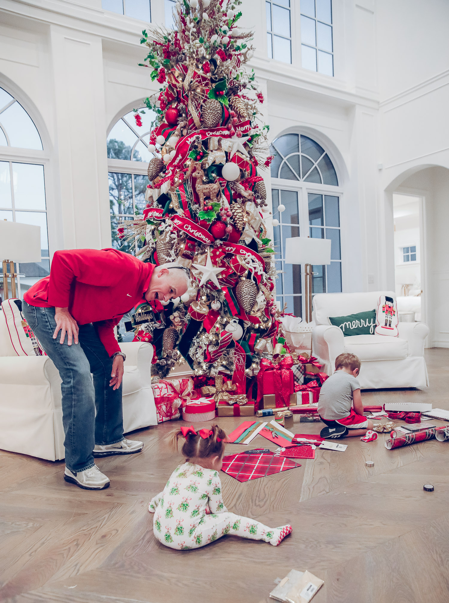 walmart gift wrap christmas 2020, shop hello holidays christmas tree, magnetic me PJs, emily ann gemma-10 |Gift Wrapping Ideas by popular US life and style blog, The Sweetest Thing: image of a little girl wearing Magnetic Me Christmas pjs sitting on the floor with her brother  while using Christmas wrapping paper supplies spread out on the floor in front of their Christmas tree. 