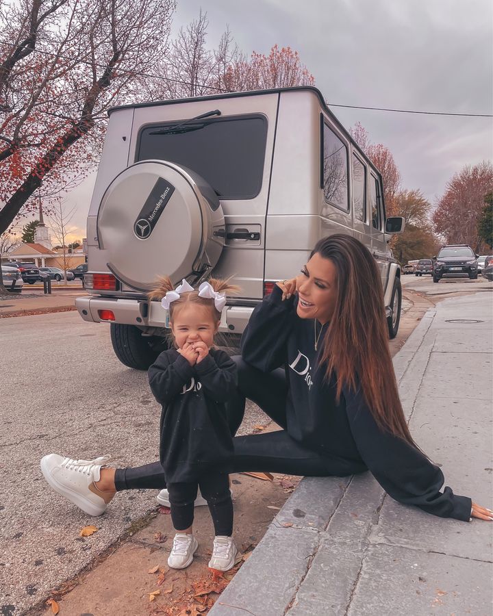 November Instagram Recap by popular US lifestyle blog, The Sweetest Thing: image of Emily Gemma sitting on a curb with her daughter Sophie and wearing a pair of black Spanx leggings, black Dior sweatshirt, white platform sneakers, and Gorjana necklace. 