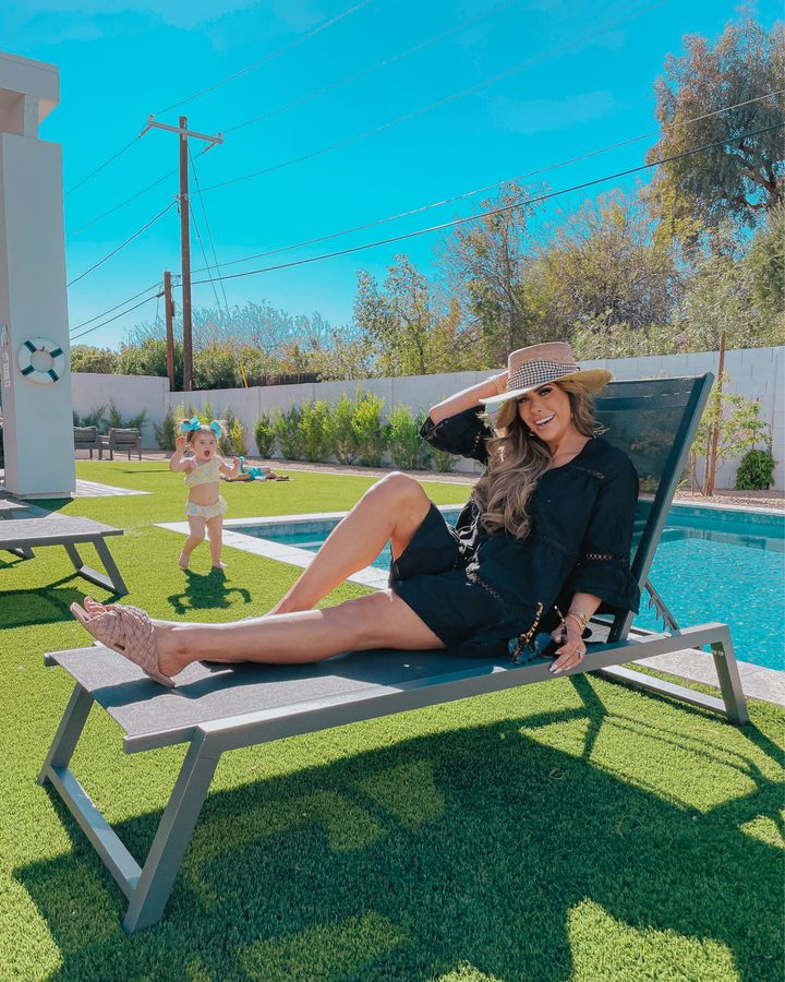 Poolside style, scottsdale fashion blog, Emily gemma, swim cover up, best bikinis spring summer 2021, sunglasses, Steve Madden sandals |February Instagram Recap by popular US life and style blog, The Sweetest Thing: image of Emily Gemma sitting on a lounge chair next to a outdoor swimming pool and wearing a black H&M coverup, Lack of Colors hat, and Steve Madden slide sandals. 