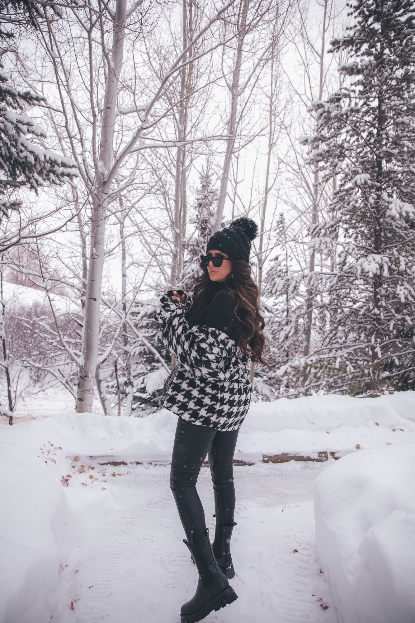 lug sole boots chelsea boots, winter outfit idea snow jackson hole, emily gemma | Lug Sole Boots by popular US fashion blog, The Sweetest Thing: image of Emily Gemma wearing a Storets black and white houndstooth jacket, Good American bodysuit, BlankNYC faux leather pants, Steve Madden black lug sole boots, BP. sunglasses, TopShop black pom beanie, Chanel handbag, Monica Vinader ring, Rolex watch, Cartier bracelets, and Iconic Nude' + KIM K.W. + White Russian Sparkle lip combo. 