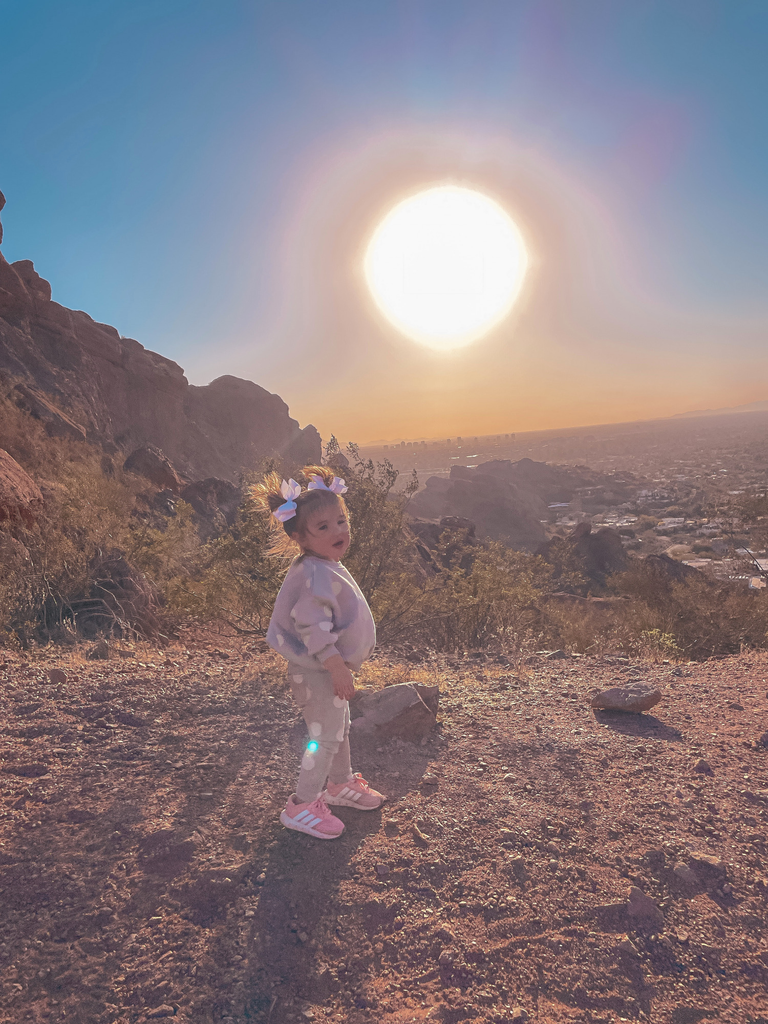 Hiking Outfits by popular US fashion blog, The Sweetest Thing: image of a little girl standing outside and wearing a grey and white polka dot lounge set, sneakers, and matching white hair bows. 