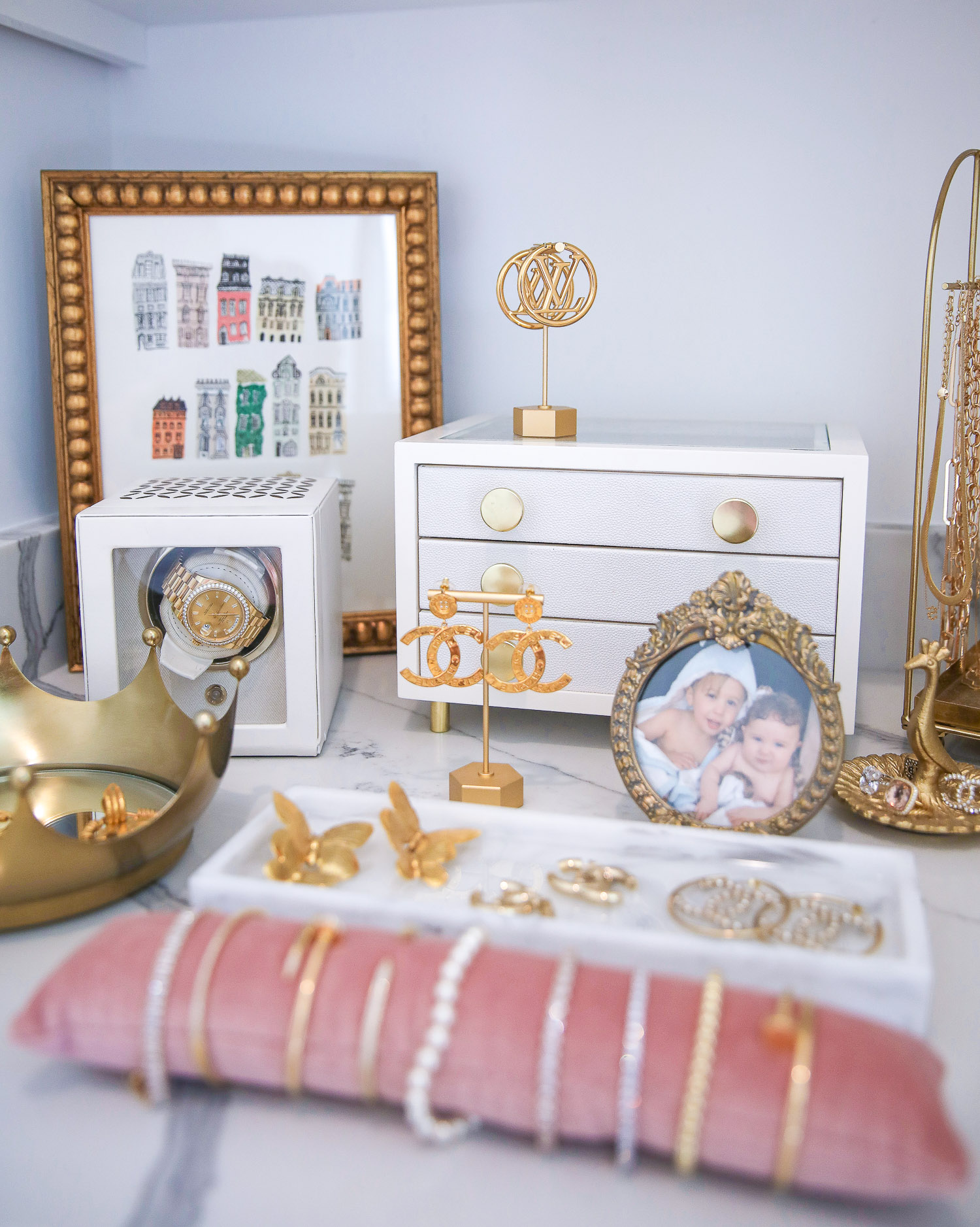 Amazon Must Haves by popular US life and style blog, The Sweetest Thing: image of gold picture frames, gold jewelry holders, white jewelry box, pink velvet bracelet cushion, and gold necklace holder on a white marble counter top. 