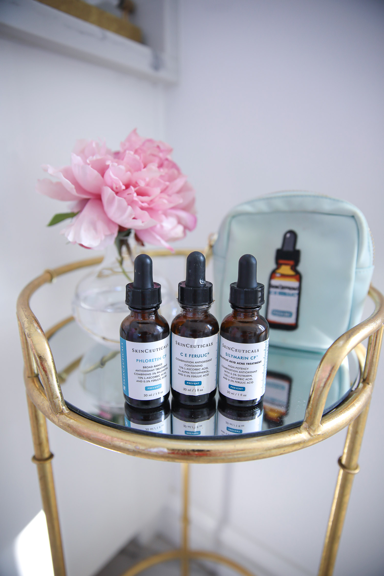 Skinceuticals CE Ferulic SilyMarin Phloretin CF, best Vitamim C serum, CE Ferulic vs Phloretin CF, why do you need Vitamin C, emily gemma skincare |Vitamin C Skincare by popular beauty blog, The Sweetest Thing: image of SkinCeuticals vitamin c bottles on a gold and glass side table. 