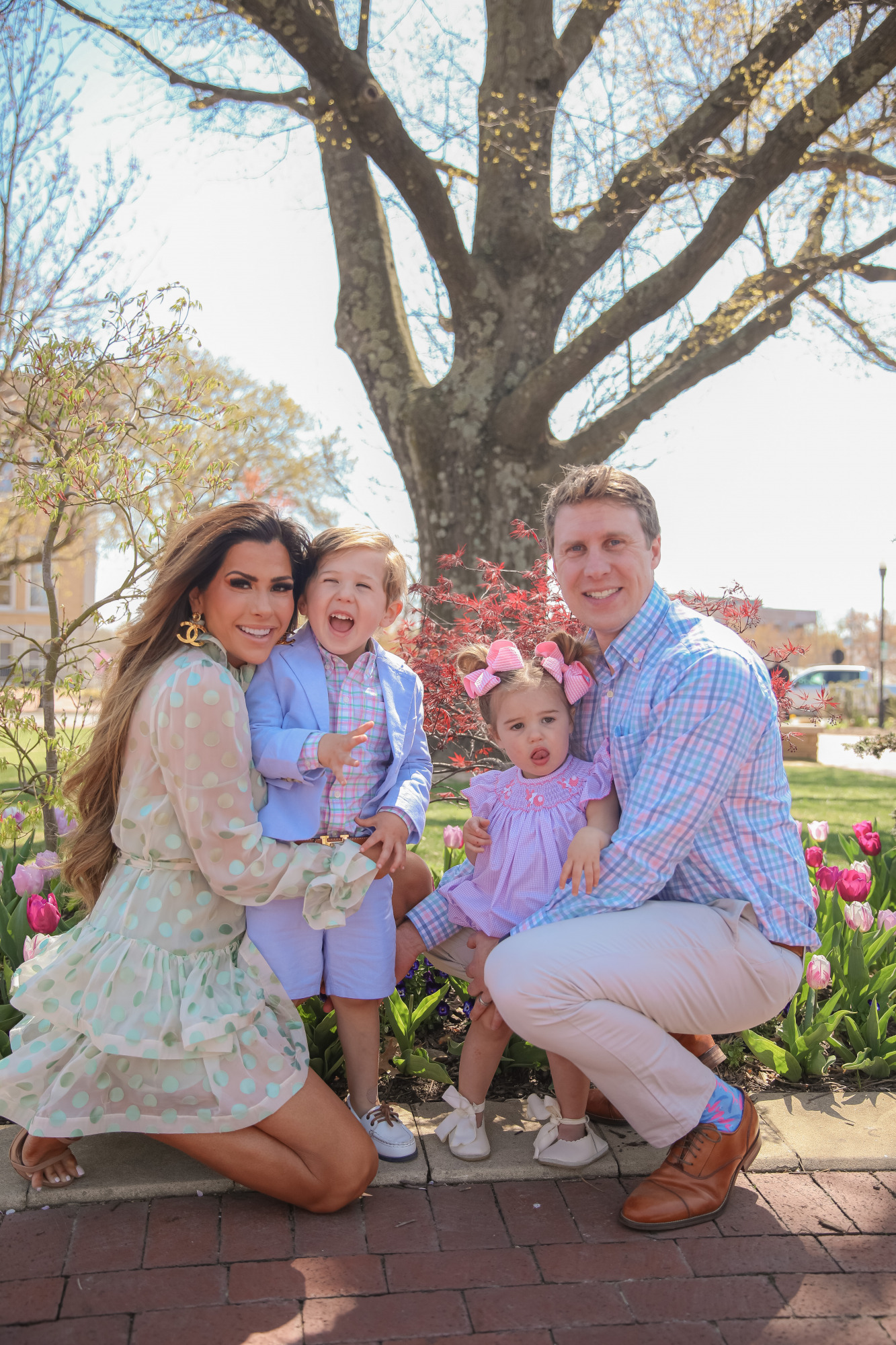 Zimmermann dress, family easter outfit photos, toddler fashion outfit spring summer 2021, Emily Gemma | April Instagram Recap by popular US fashion blog, The Sweetest Thing: image of Emily Gemma, her two kids and her husband kneeling together outside and wearing a cream and blue polka dot print dress, pink and blue plaid button up shirt, tan slacks, pink dress, pink hair bows, blue blazer, blue shorts, and white boater shoes. 
