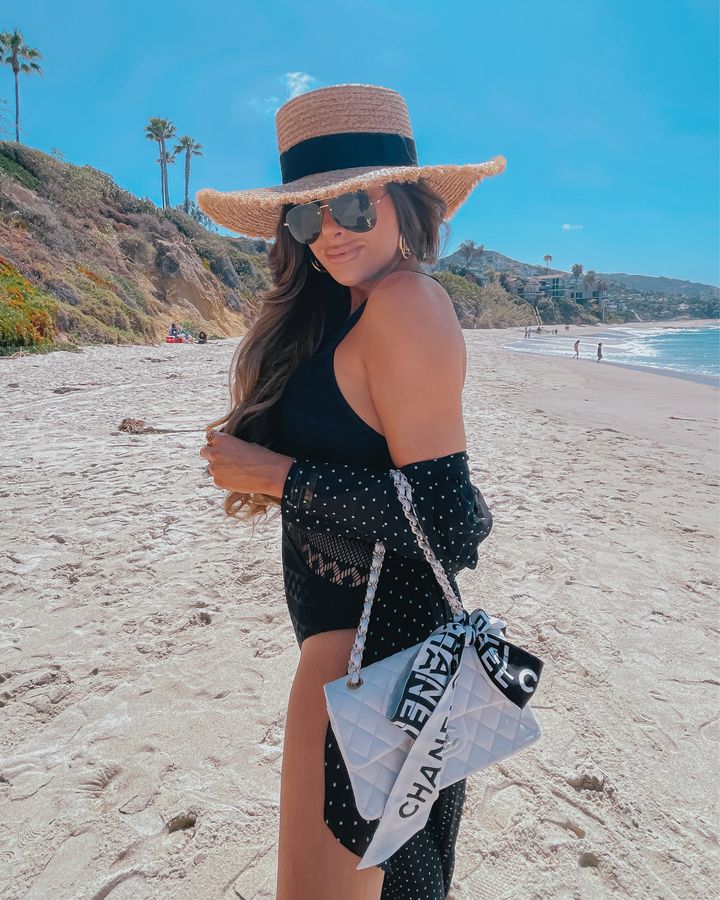 Emily Ann Gemma beachwear, one piece black flattering swimsuit, flattering swimsuit ideas, black swim cover up, express outfit ideas, white chanel handbag, chanel silk scarf, straw beach hat with black band, black and white kimono cover up | Instagram Recap by popular US life and style blog, The Sweetest Thing: image of Emily Gemma standing on a beach and wearing a black one piece swimsuit, straw boater hat, YSL aviator sunglasses, black and white polka dot coverup and holding a white quilted handbag. 