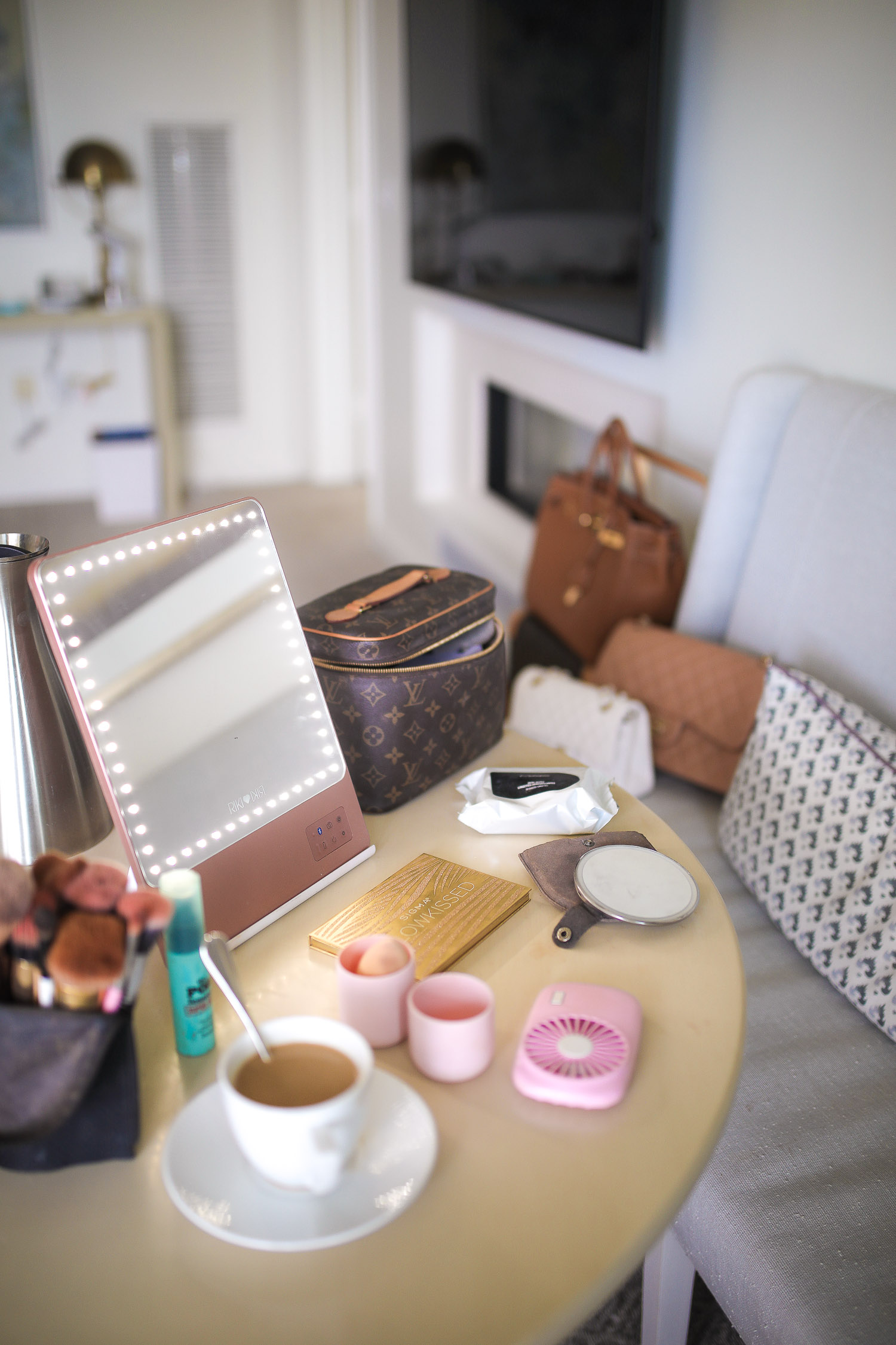 Riki Size Travel Mirror, pink travel fan makeup, beauty sponge holder travel amazon, Louis Vuitton Nice Case, Emily Gemma | Travel Hacks by popular life and style blog, The Sweetest Thing: image of a makeup mirror, Louis Vuitton makeup bag, makeup brush holder, cup of coffee, portable hand fan, beauty blender, and makeup pallet. 