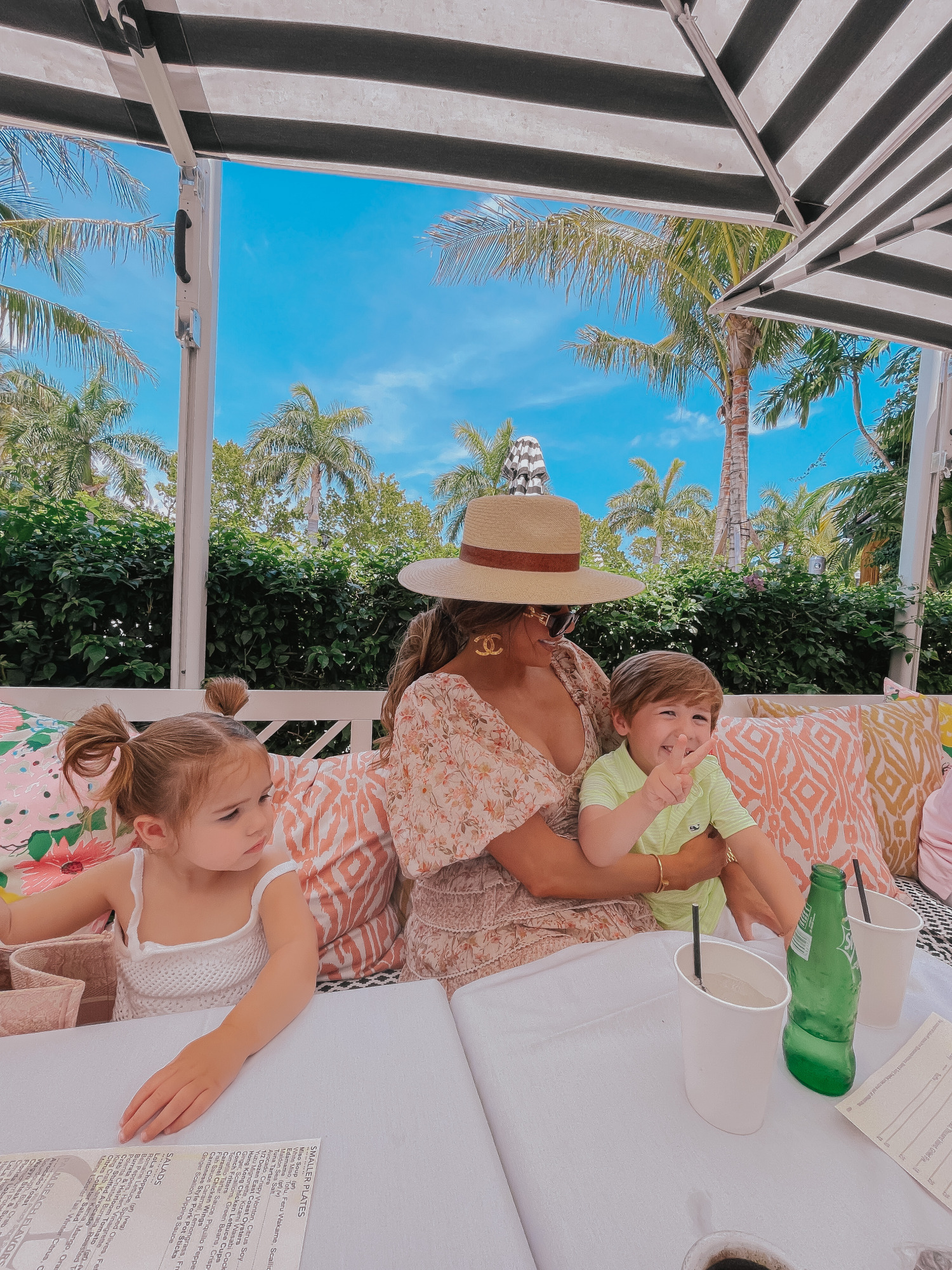 Palm beach white elephant lola41, cute outfit ideas palm beach, Emily gemma1 | Lola 41 by popular US fashion blog, The Sweetest Thing: image of Emily Gemma and her daughter Sophie and son Luke sitting outside and eating food at Lola 41 while wearing Tularosa Shaylee dress, Paris Large Button Chanel Earrings, dior pink toile small book tote, Louis Vuitton Edge Sunglasses, chanel gold button earrings, Rag and Bone hat, Cartier bracelets, Janie and Jack white tank top, and Vineyard Vines polo shirt.  