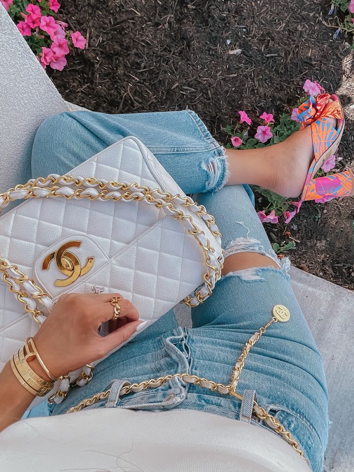 white chanel handbag, white and gold chanel handbag, tropical bright colored heels, cropped jeans, cream color bodysuit, vintage chanel belt, Emily Ann gemma, warm weather outfit ideas, summer outfit ideas 2021 | Instagram Recap by popular US life and style blog, The Sweetest Thing: image of Emily Gemma wearing tropical print black heel sandals, light wash distressed high waist denim and holding a white quilted Chanel handbag. 
