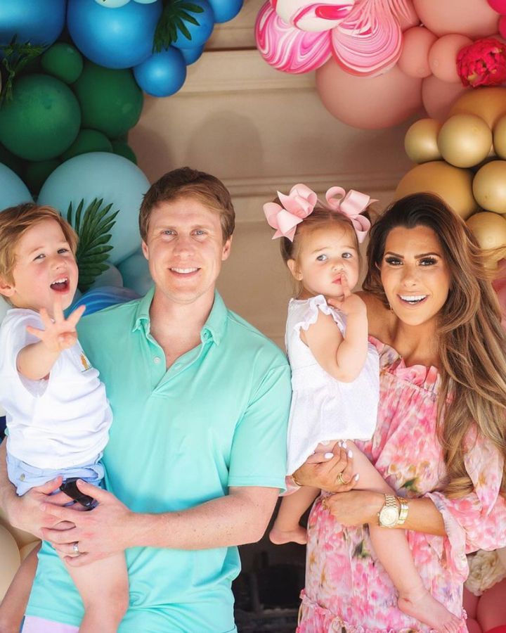 John and Emily Gemma, The Gemma Gang, Kids Birthday Party ideas, Dino birthday party, four year old birthday party, two year old birthday party, happy birthday smocked bubble, floral print dress | Instagram Recap by popular US life and style blog, The Sweetest Thing: image of Emily Gemma and her husband standing together and holding their young son and daughter under a rainbow balloon garland. 