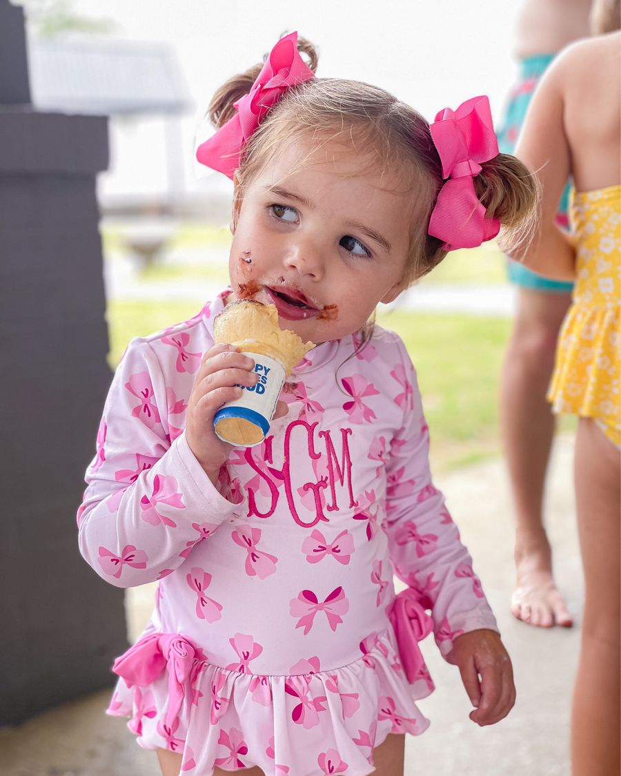 baby girl swimsuit ideas, pink bow swimsuit, little girl's swimsuits, smocked auctions, best bows for little girls, amazon bows, Sophia gemma, the gemma gang, Emily ann Gemma  | June Instagram Recap by popular US fashion blog, The Sweetest Thing: image of a little girl wearing a monogramed pink bow print swimsuit and eating a chocolate ice cream cone. 
