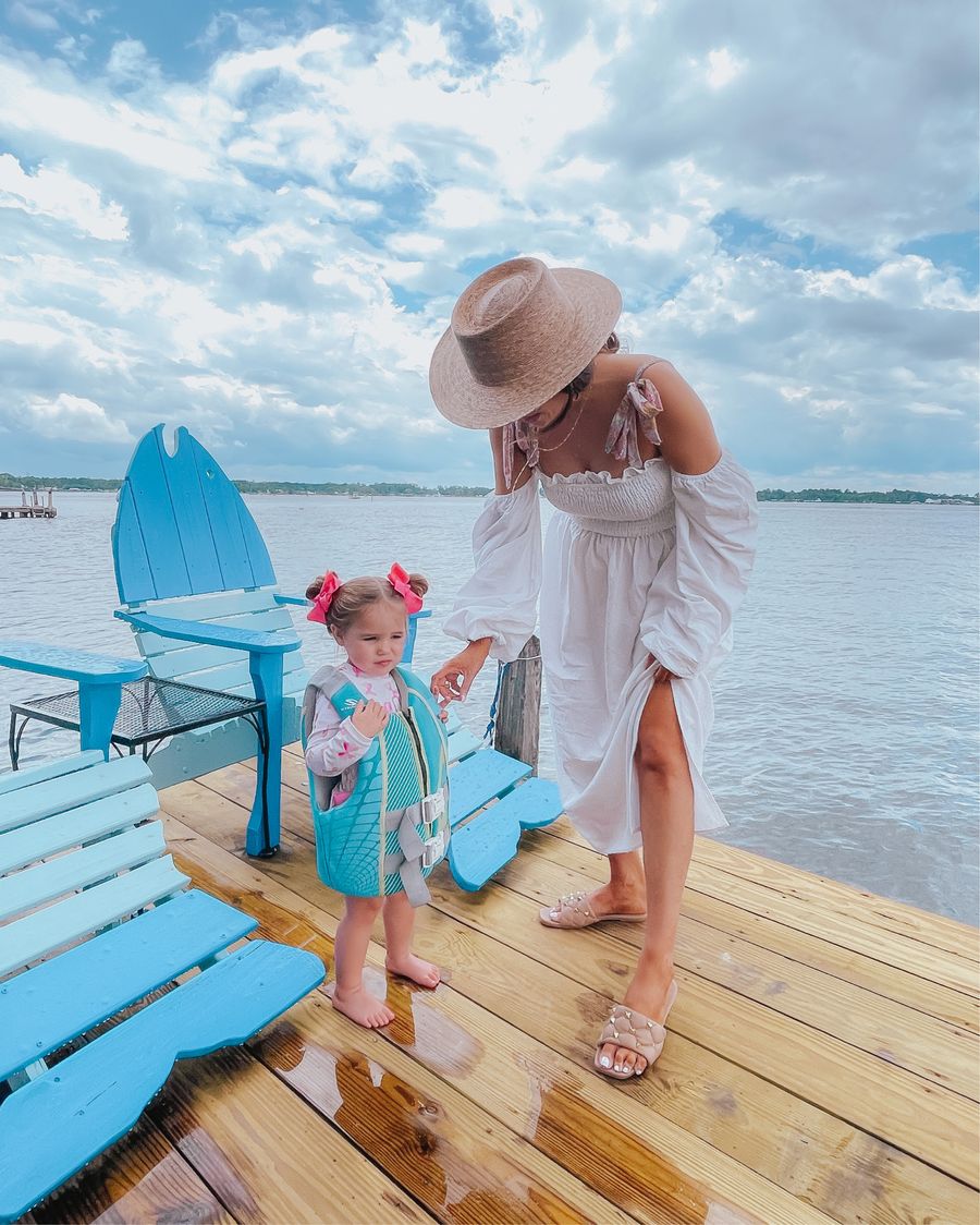 summer outfit ideas 2021, best swimsuits, floral swimsuit, affordable swim cover up, best summer sandals, nude sandals, valentine dupe sandals, best summer hats, Emily ann gemma | June Instagram Recap by popular US fashion blog, The Sweetest Thing: image of Emily Gemma and her daughter Sophie standing on a pier next to some blue wooden chairs shaped like fish. 