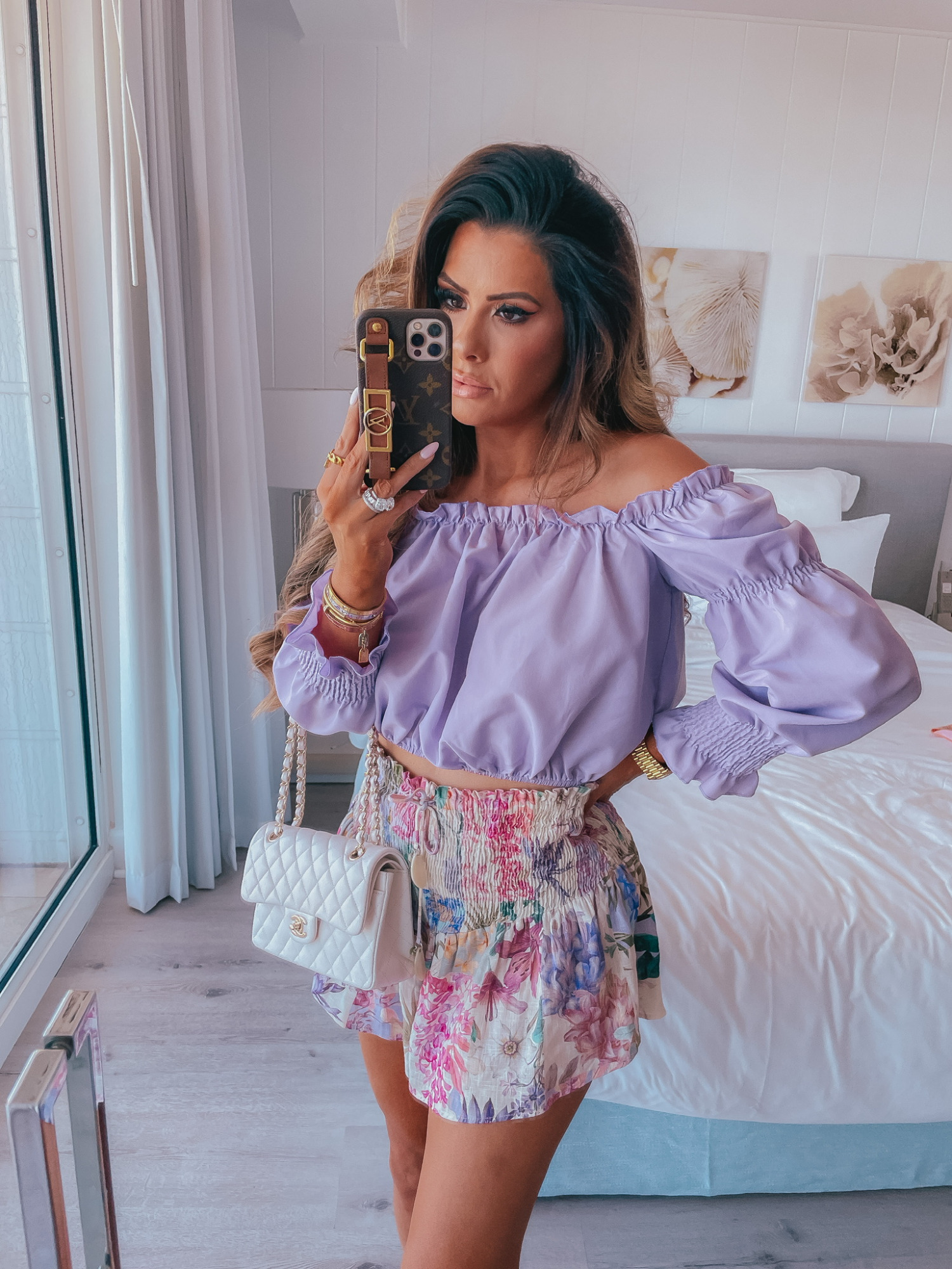 Purple off the shoulder top, nasty gal top, white chanel handbag, floral shorts with elastic waistband, Emily Ann gemma, Louis Vuitton phone case, beach outfit ideas | Instagram Recap by popular US life and style blog, The Sweetest Thing: image of Emily Gemma wearing a purple off the shoulder long sleeve top, white floral print shorts and holding a white quilted handbag. 