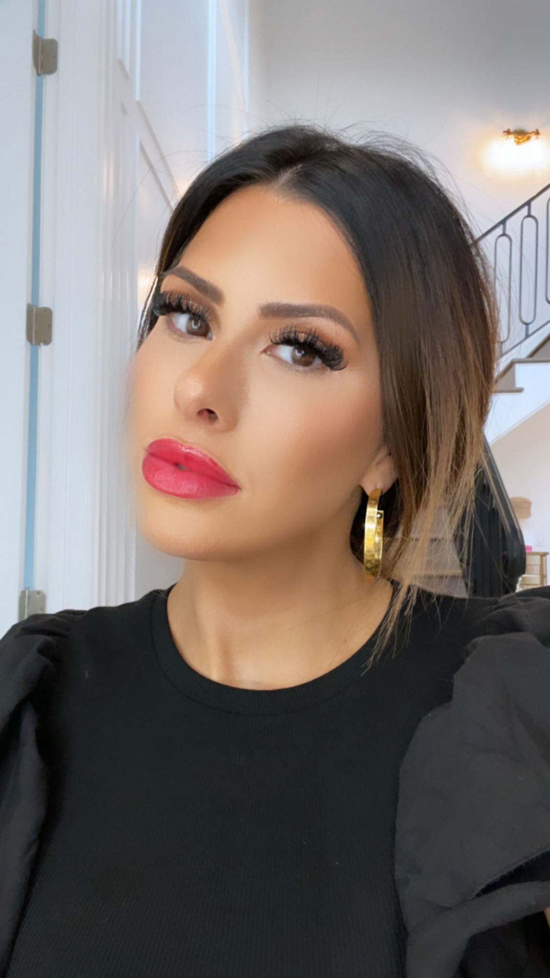 Emily-ann-gemma-makeup-review-ysl-lipstick-ltk-day-sale | LTK Sales by popular US fashion blog, The Sweetest Thing: image of Emily Gemma wearing gold hoop earrings, red lipstick and black puff sleeve top. 
