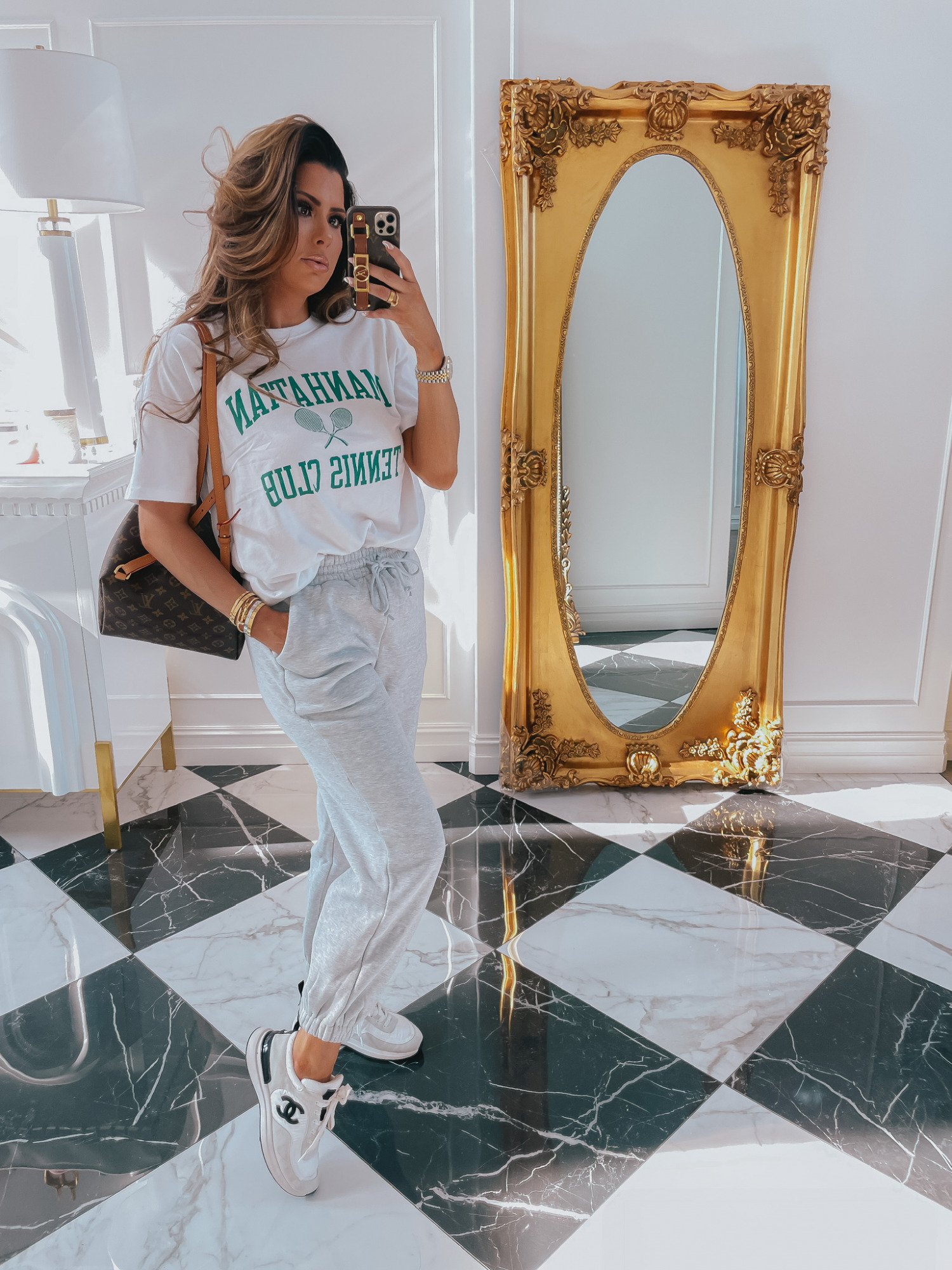Emily-ann-gemma-abercrombie-tee-shirt-sweatpants-outfit-ltk-day-sale | LTK Sales by popular US fashion blog, The Sweetest Thing: image of Emily Gemma wearing a Manhattan Tennis Club shirt, grey sweatpants and sneakers. 