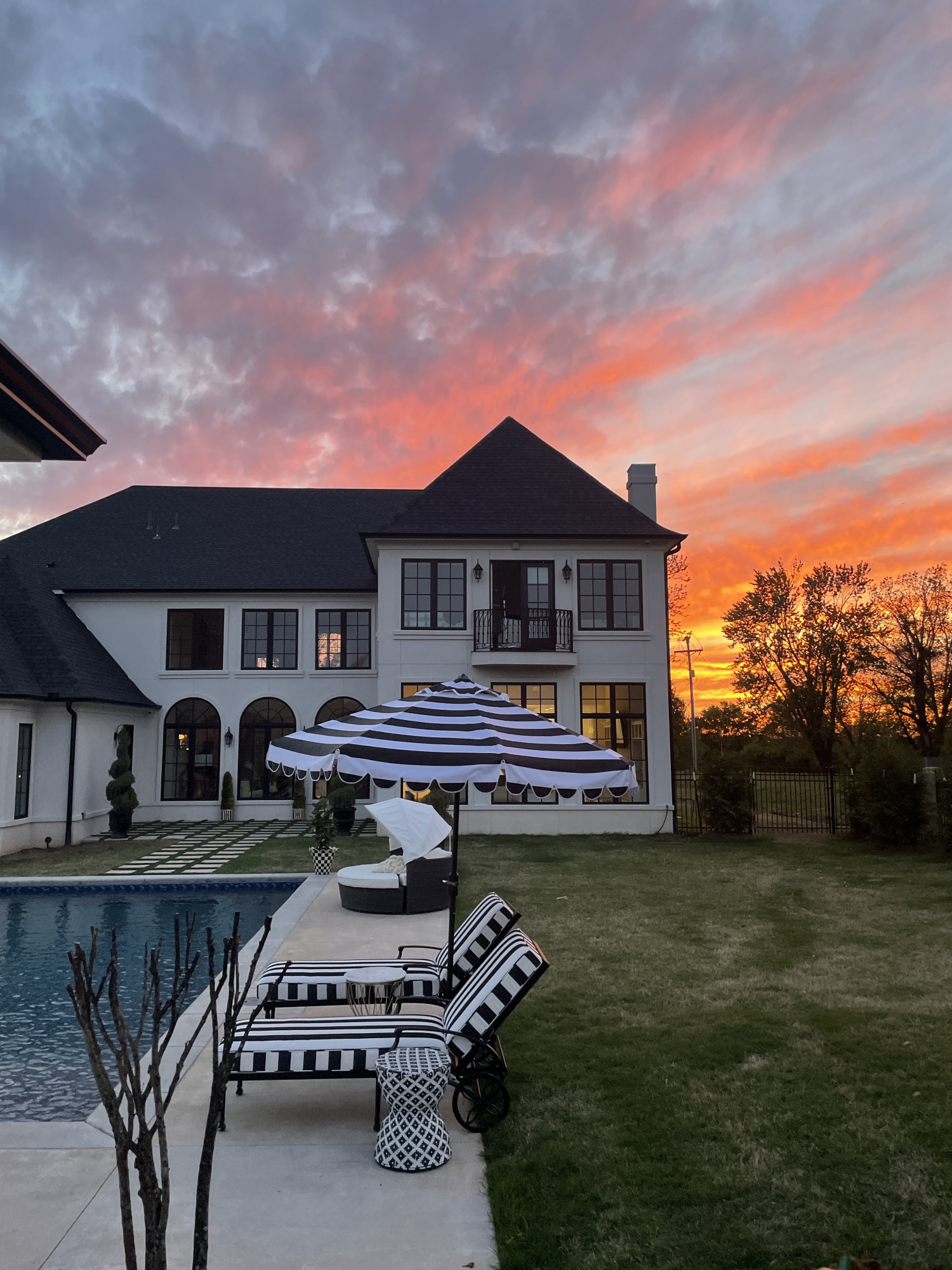 outdoor decor, patio decor, swimming pool, Emily ann gemma home | Instagram Recap by popular US life and style blog, The Sweetest Thing: image of a back yard with a swimming pool, lounge chair with black and white stripe cushions, black and white side table, and and back and white stripe shade umbrella. 