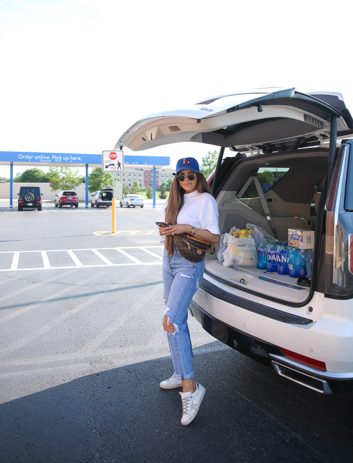 Emily ann gemma, summer outfit ideas, agolde jeans, golden goose sneakers, best white tee, white t-shirt from Nordstrom, casual outfit ideas | June Instagram Recap by popular US fashion blog, The Sweetest Thing: image of Emily Gemma standing next to her car that's filled with groceries and wearing a LA ball cap, white mock neck top, distressed jeans, and Golden Goose Sneakers. 