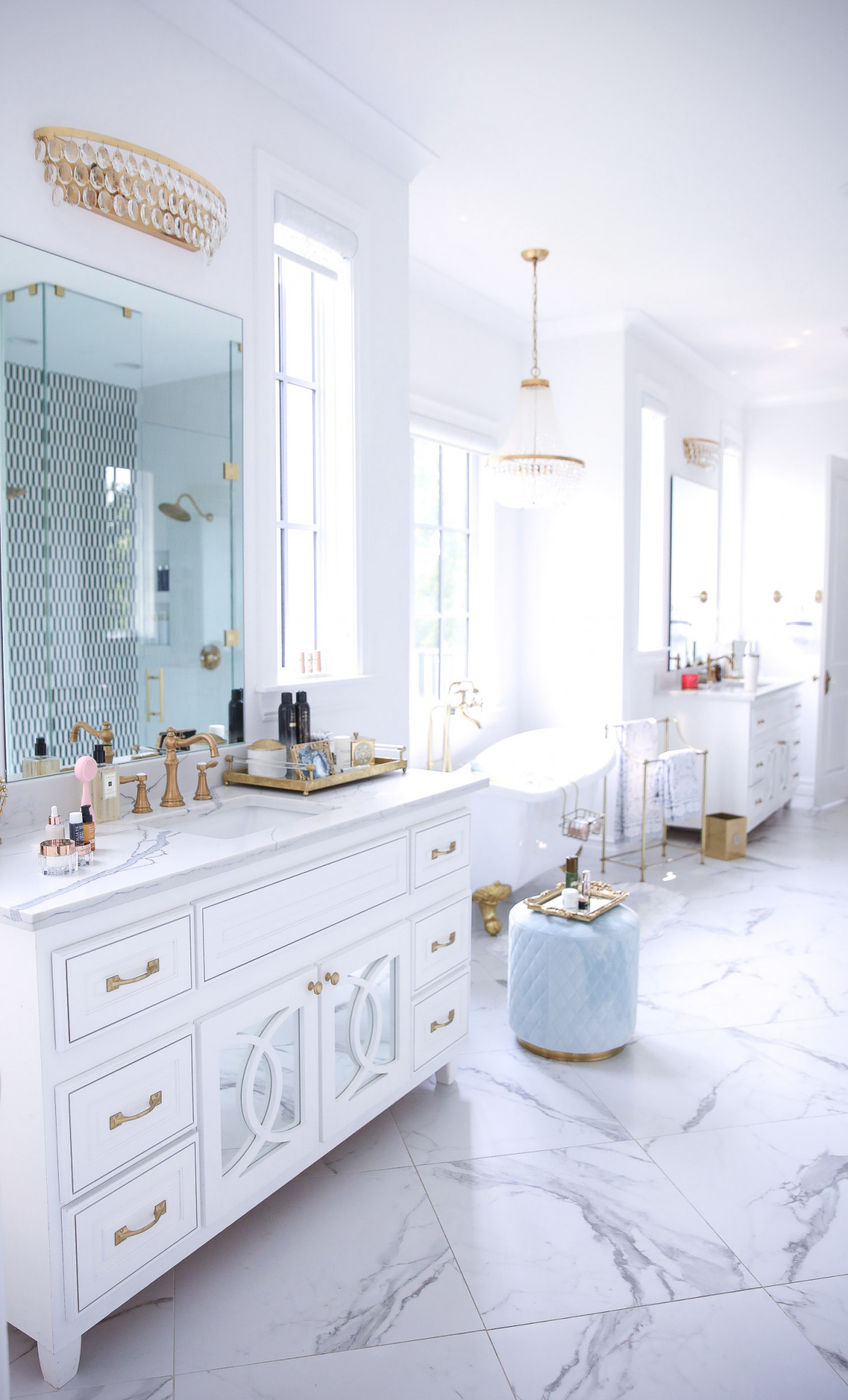 Delina Parfum de Marly set NSALE 2021, Emily gemma master bathroom, Nordstrom anniversary sale 2021 beauty must haves, anthropologie bathrom decor 2021, pinterest bathroom all white gold | Instagram Recap by popular US life and style blog, The Sweetest Thing: image of a master bathroom with double white vanities, gold and crystal chandelier, blue tuft ottoman, white and gold clawfoot tub, and gold mirrored bathroom tray. 