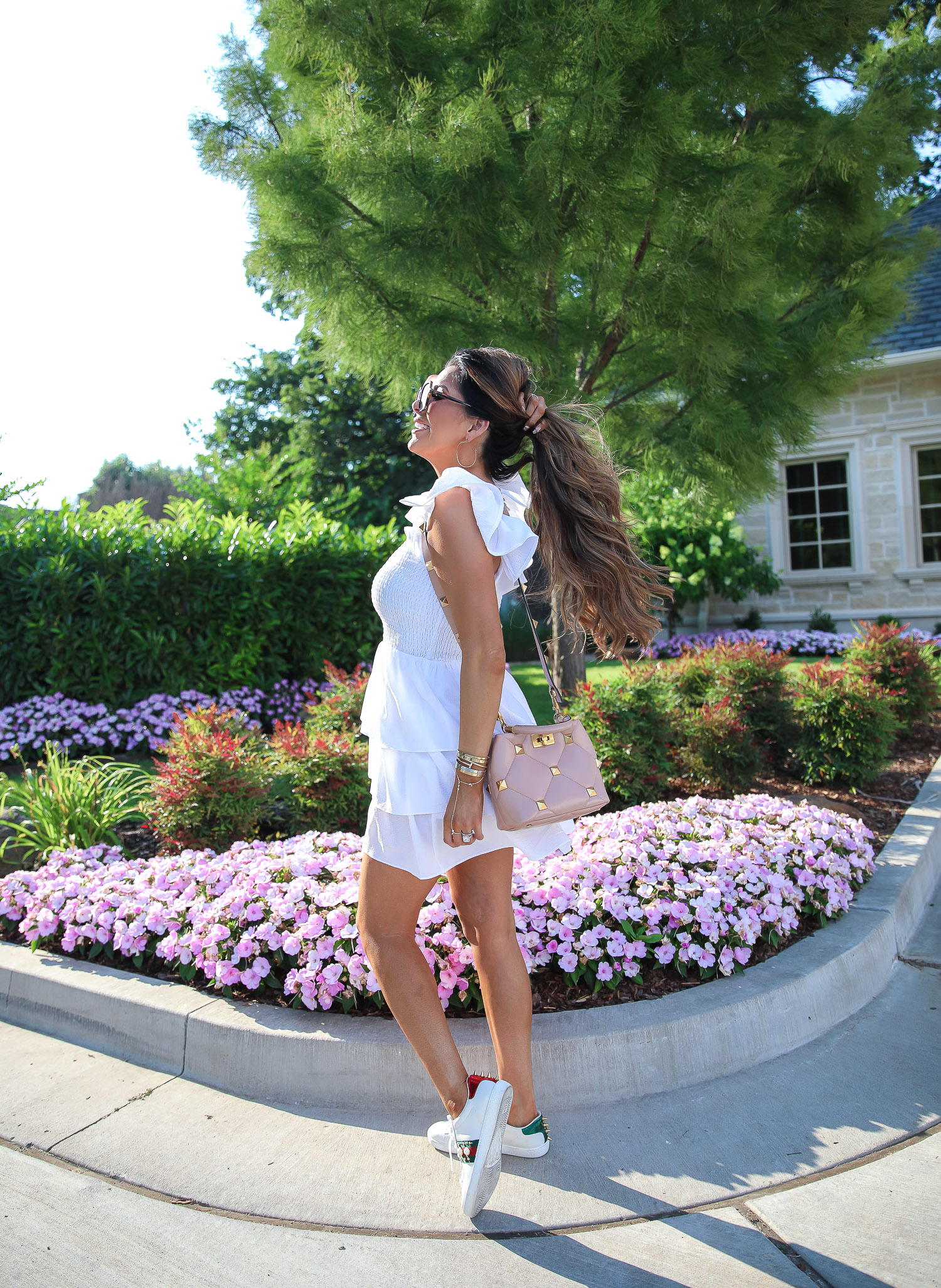 Love Shack Fancy by popular US fashion blog, The Sweetest Thing: image of Emily Gemma wearing a white Express dress, Express sunglasses, Rolex watch, gold bracelets, gold hoop earrings, Gucci sneakers, and holding a Valentino bag.  