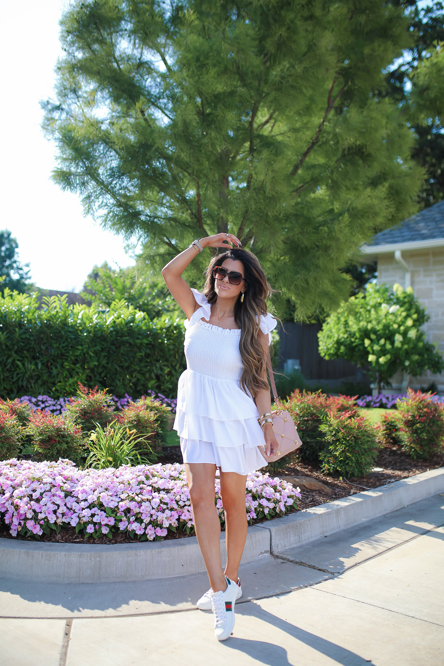 Love Shack Fancy by popular US fashion blog, The Sweetest Thing: image of Emily Gemma wearing a white Express dress, Express sunglasses, Rolex watch, gold bracelets, gold hoop earrings, Gucci sneakers, and holding a Valentino bag.  