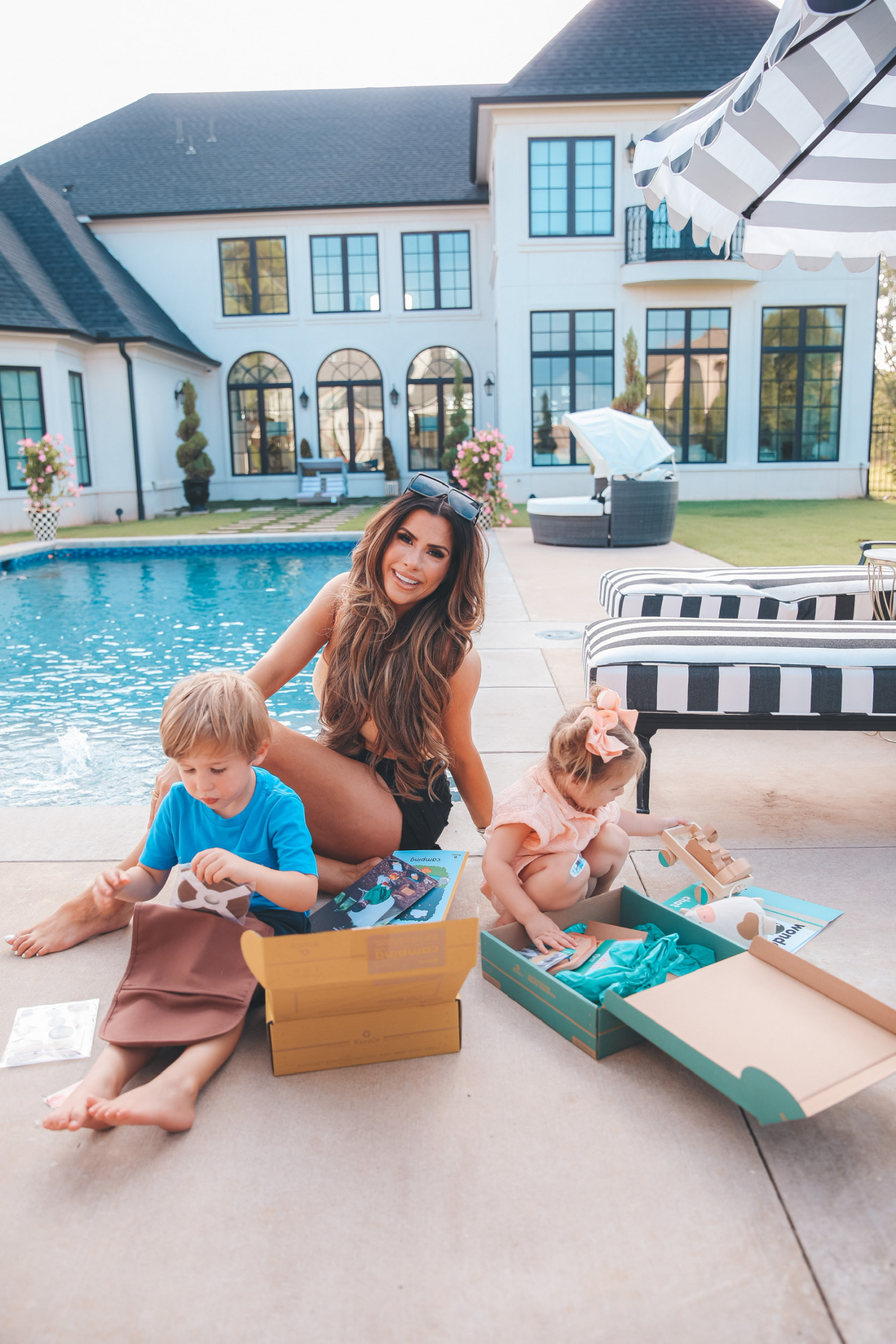 Emily Ann Gemma Family, Luke Gemma, Sophia Gemma, Kids Toys, Kids Educational Toys, KiwiCo. , Best toys and activities for kids, summer activities for kids | Instagram Recap by popular US life and style blog, The Sweetest Thing: image of Emily Gemma and her two kids sitting by their pool and opening some KiwiCo boxes. 