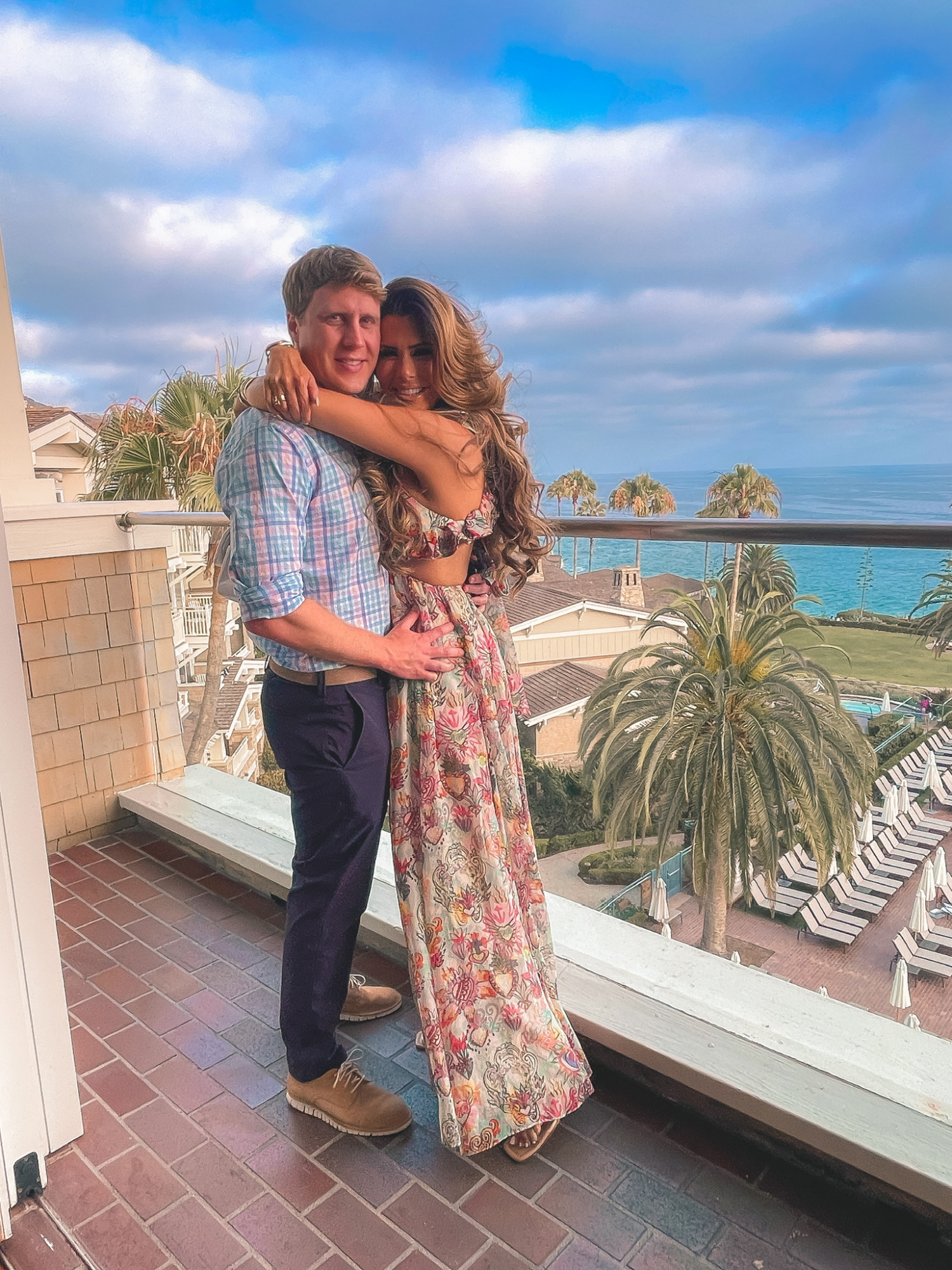 Emily and John gemma, Zimmermann dress, vacation outfit ideas | Instagram Recap by popular US life and style blog, The Sweetest Thing: image of Emily Gemma wearing a tropical print Zimmerman dress and standing with her arms wrapped around her husband while standing on a deck with an ocean view. 