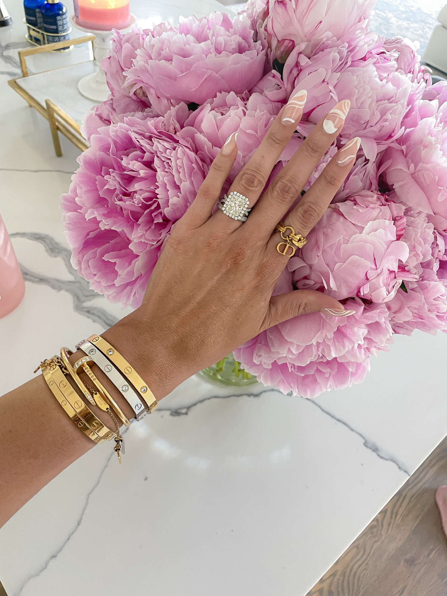Emily ann gemma engagement ring, radiant cut engagement ring, Cartier bracelet, wrist bracelet stack, dior ring, pink peonies, Emily ann gemma | June Instagram Recap by popular US fashion blog, The Sweetest Thing: image of Emily Gemma wearing a radiant cut engagement ring, gold bracelets, and gold ring. 