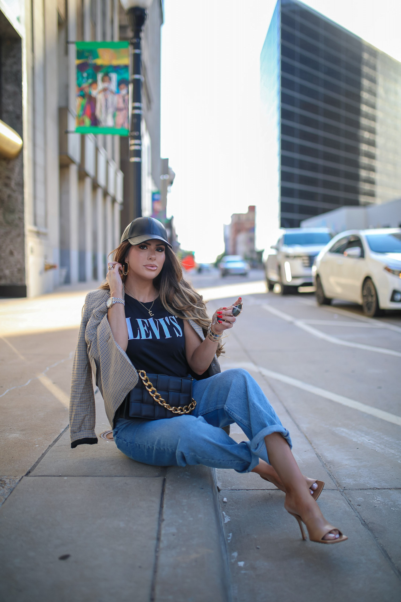 walmart fashion outfit ideas fall 2021, cute walmart outfit inspo fall, emiily gemma, tulsa fashion blogger, oversized plaid boyfriend blazer-10 | Fall Street Style by popular US fashion blog, The Sweetest Thing: image of Emily Gemma outside in a city and wearing black faux leather baseball hat, tan jacket, leaves graphic t-shirt, rolled hem jeans, and tan stiletto heel sandals. 