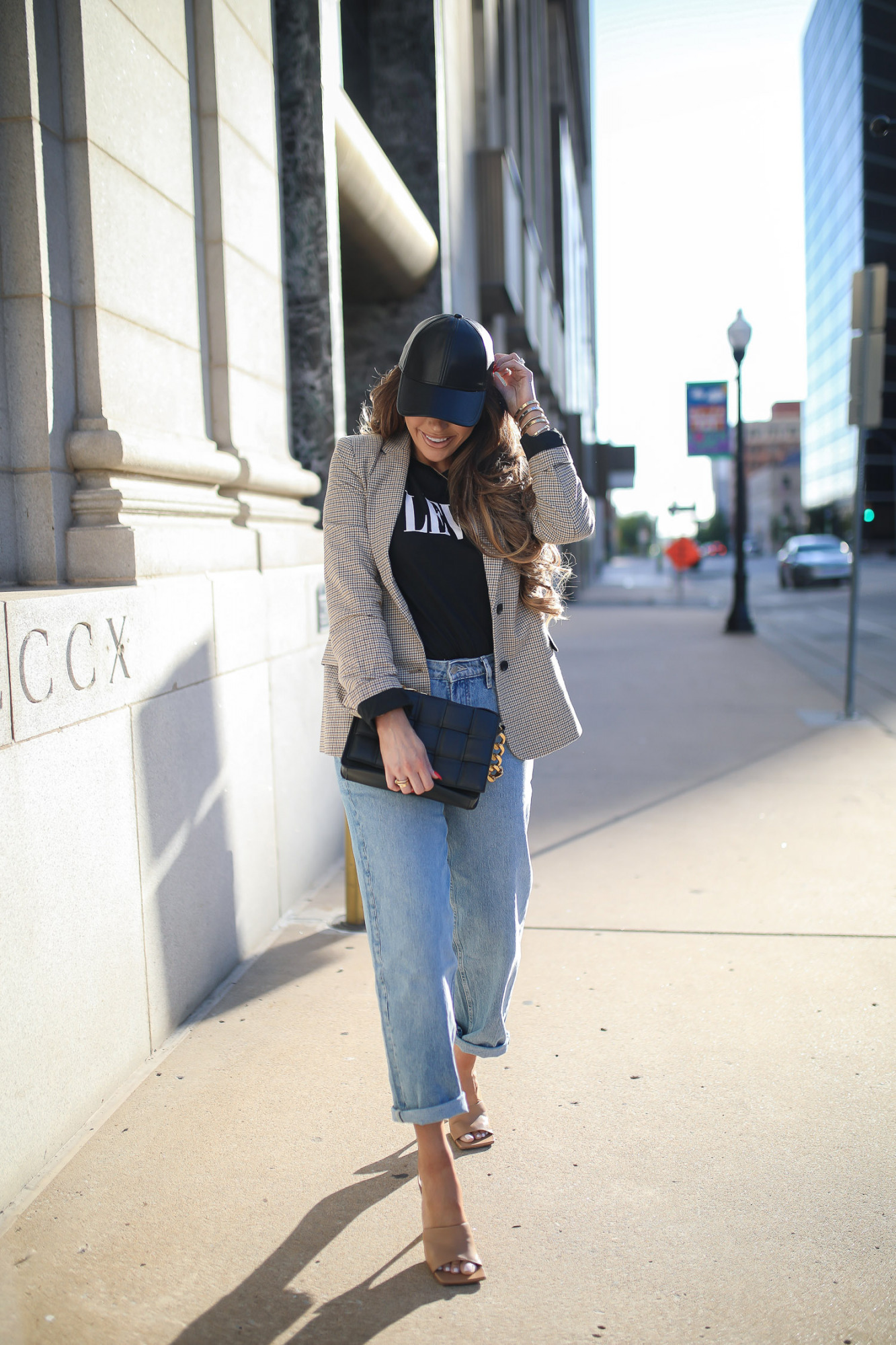 walmart fashion outfit ideas fall 2021, cute walmart outfit inspo fall, emiily gemma, tulsa fashion blogger, oversized plaid boyfriend blazer-10 | Fall Street Style by popular US fashion blog, The Sweetest Thing: image of Emily Gemma outside in a city and wearing black faux leather baseball hat, tan jacket, leaves graphic t-shirt, rolled hem jeans, and tan stiletto heel sandals. 